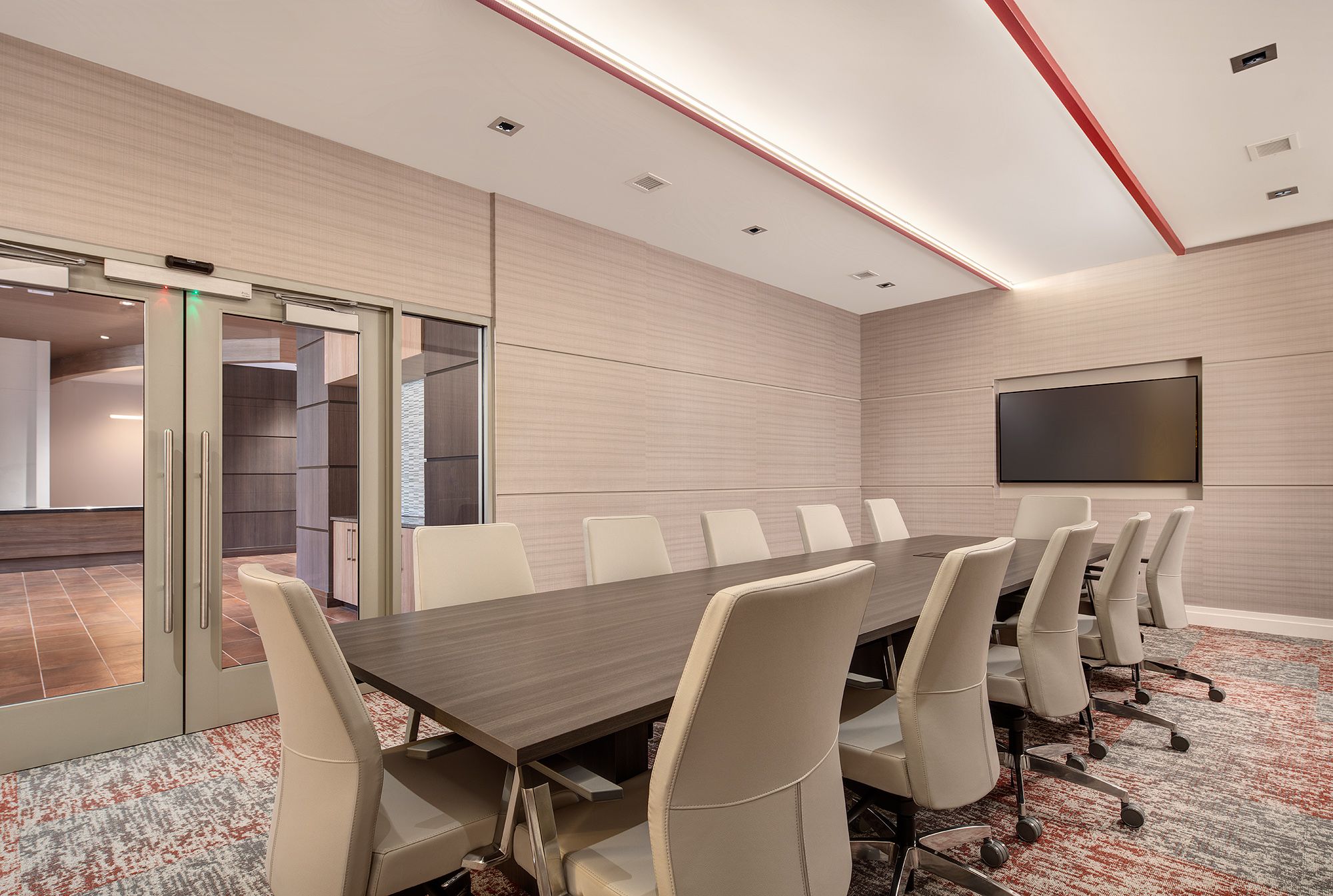 Modern conference room with a long table, chairs, and a screen.