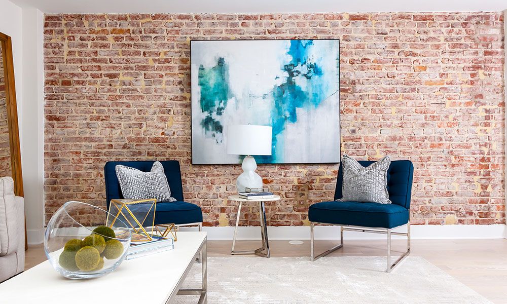 Cozy room with two blue chairs, abstract art, and a small side table.