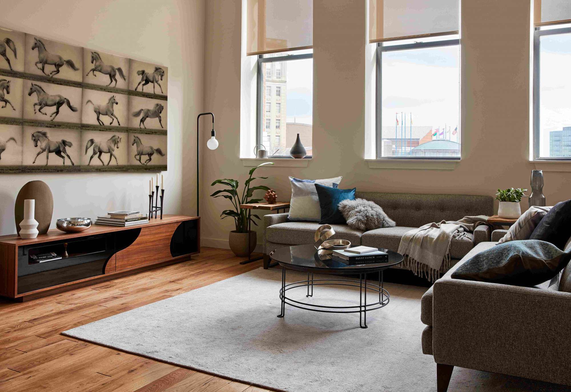 Modern living room with large windows, artwork, and stylish furniture.