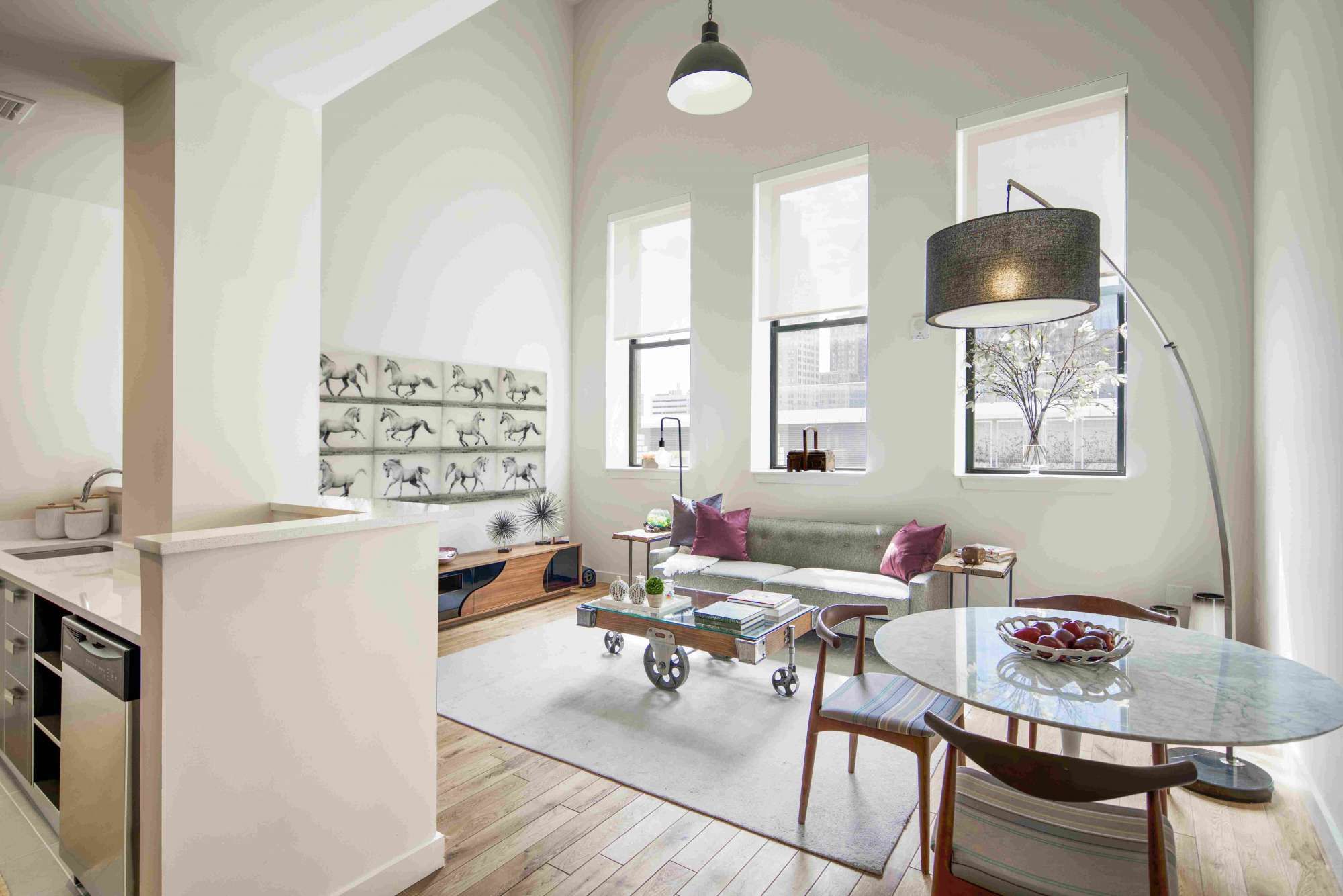 Modern living room with large windows, minimalist furniture, and a cozy dining area.