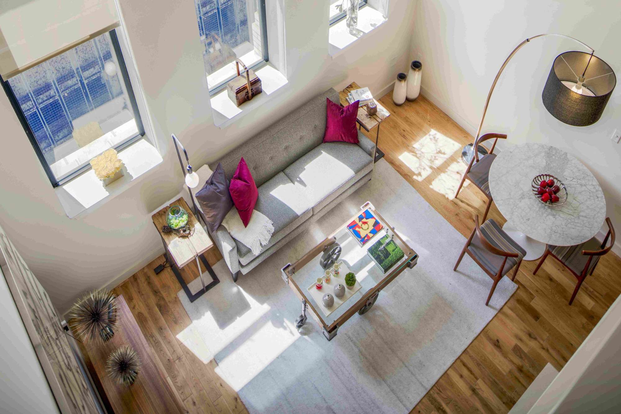 A bright, modern living space with a sofa, dining table, and large windows.