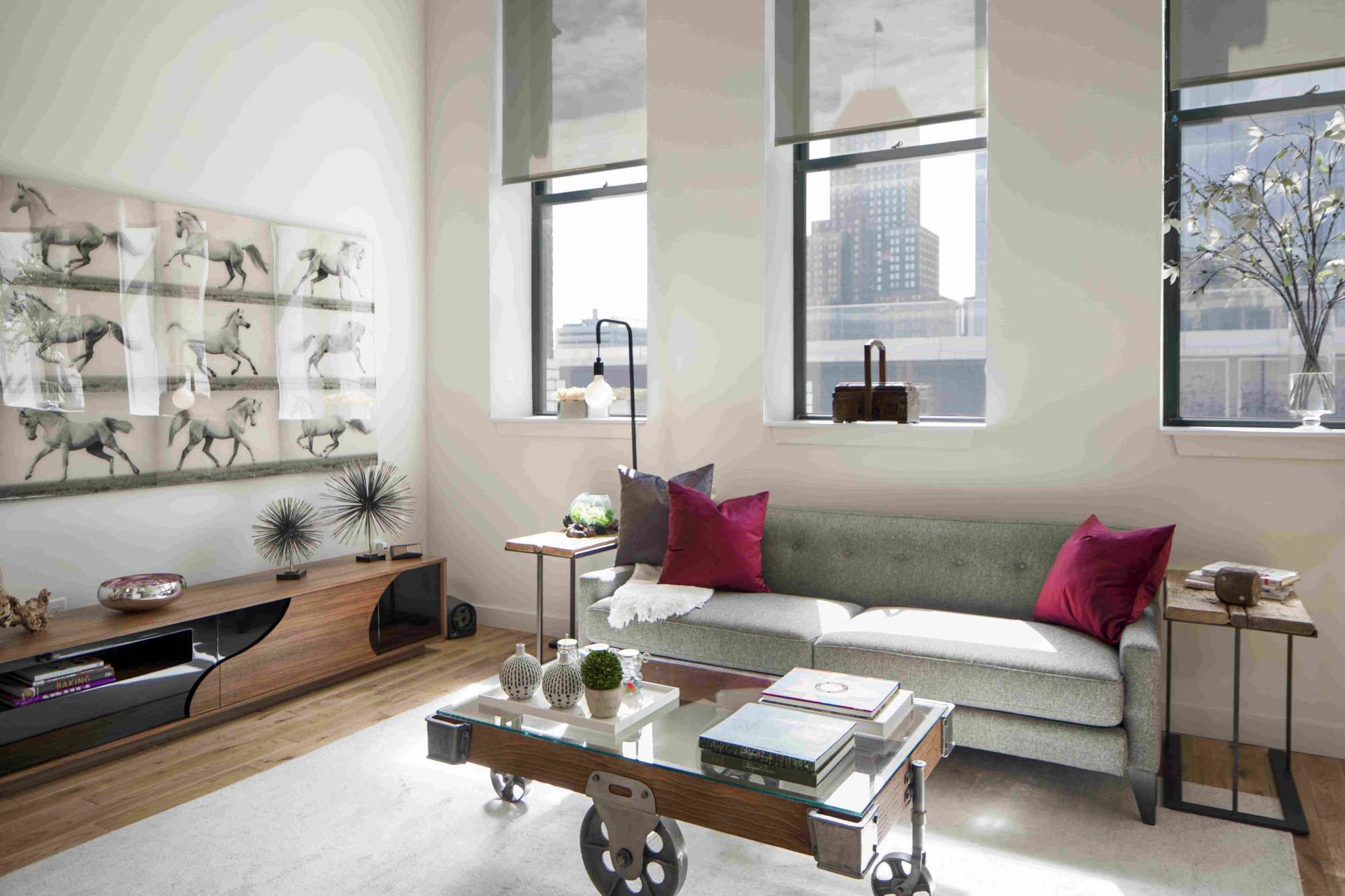 Modern living room with a green sofa, decorative pillows, and large windows.