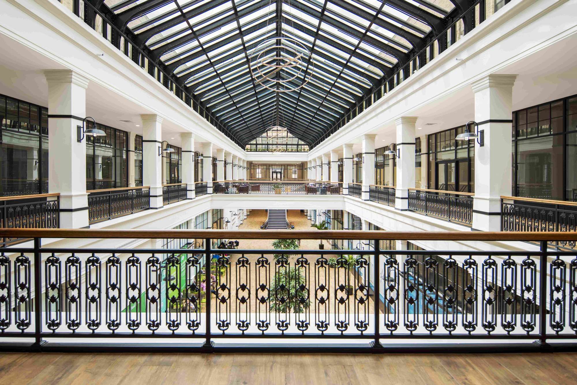 Spacious interior with glass roof, elegant railings, and greenery in a modern atrium.