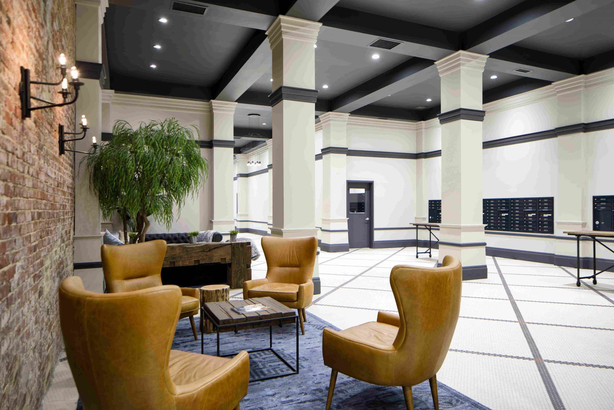 Modern lounge with yellow chairs, a small table, and a large open space featuring decorative columns.