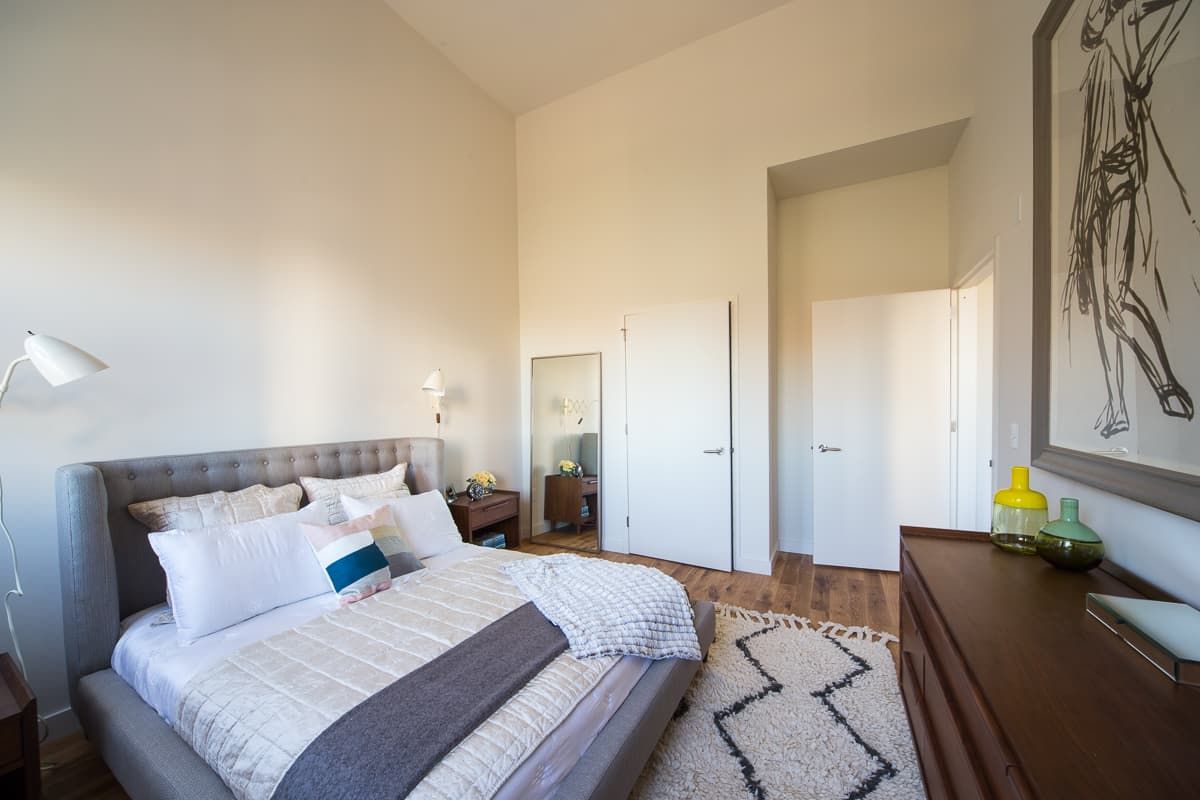 Modern bedroom with a large bed, minimalist decor, and light-colored walls.