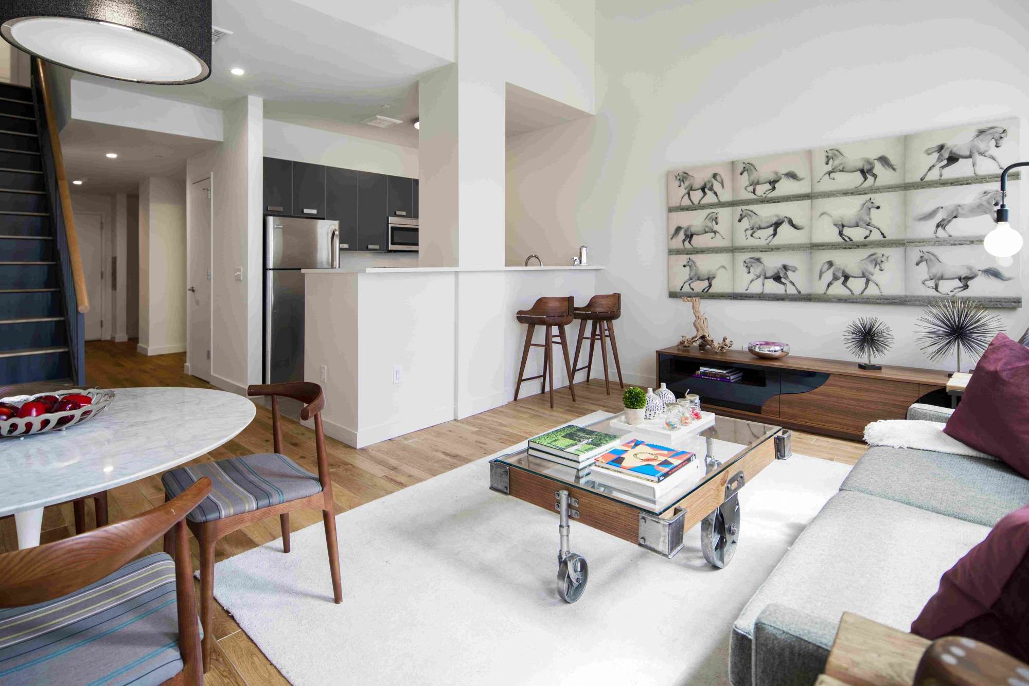 Modern living room with a dining area and open kitchen, featuring minimalist decor.