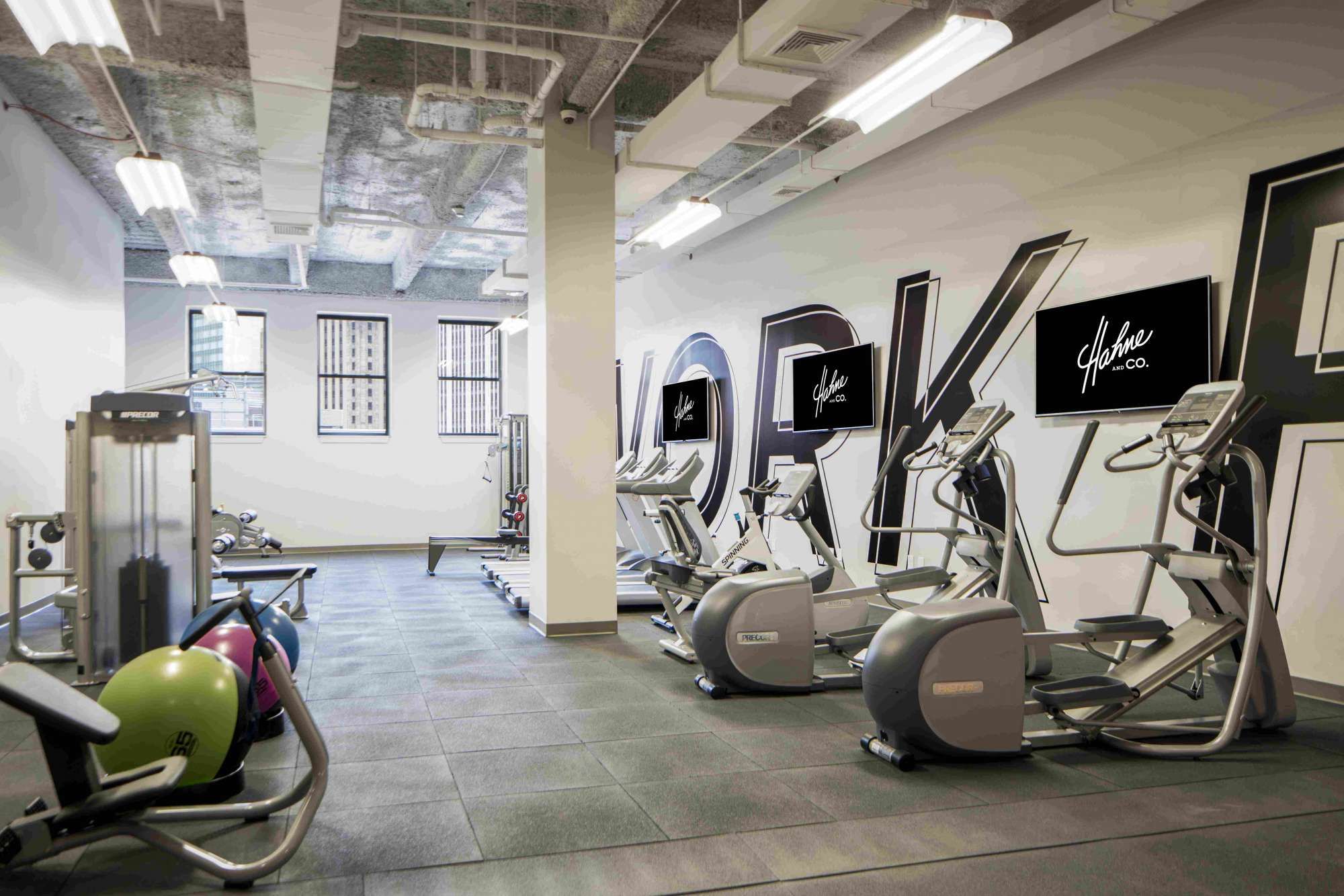 Modern gym interior with exercise equipment and motivational wall art.
