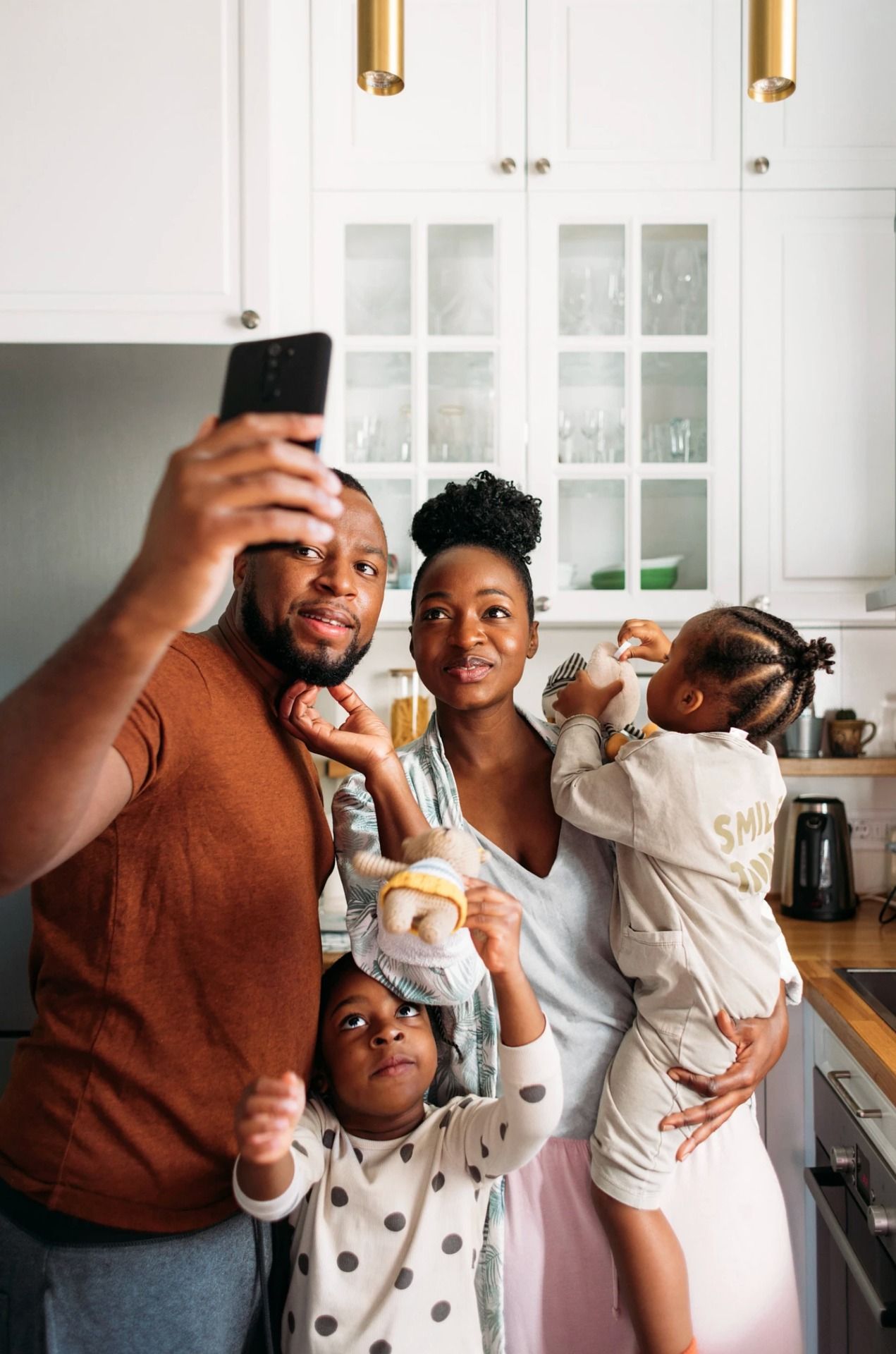 A family of four taking a selfie in their kitchen.