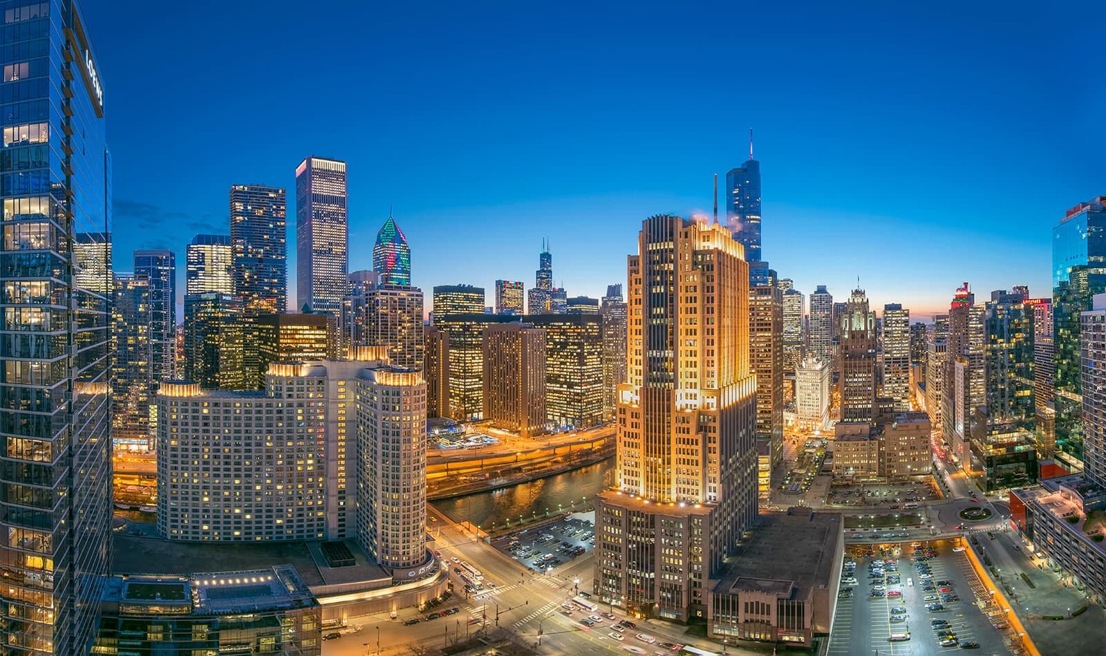 City skyline at dusk with tall buildings and a vibrant blue sky.