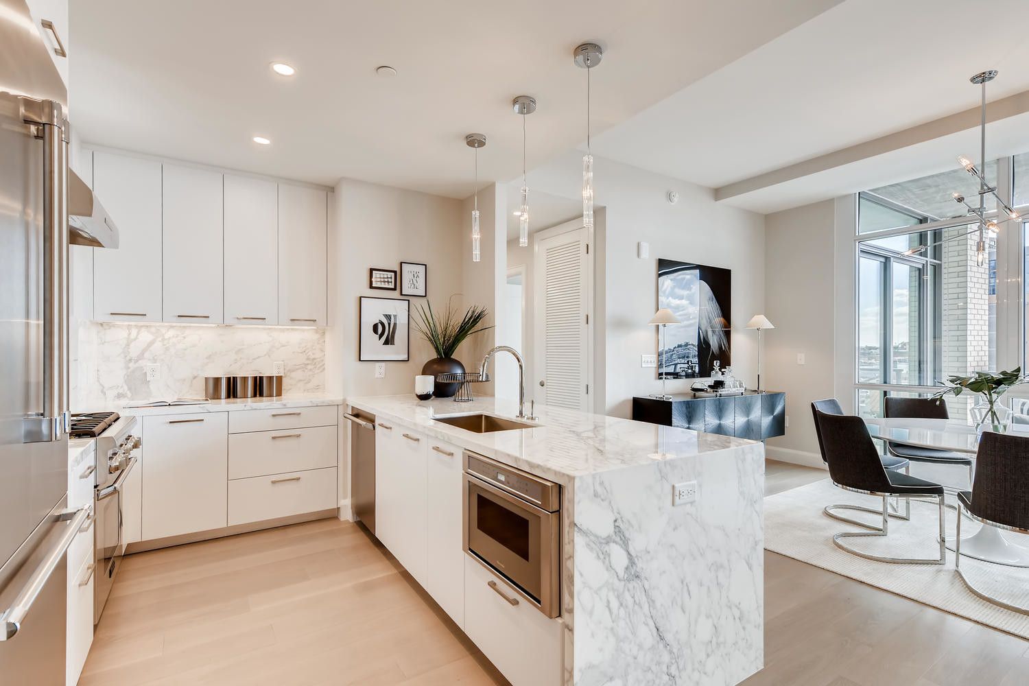 Modern kitchen with white cabinets, marble island, and stylish dining area.