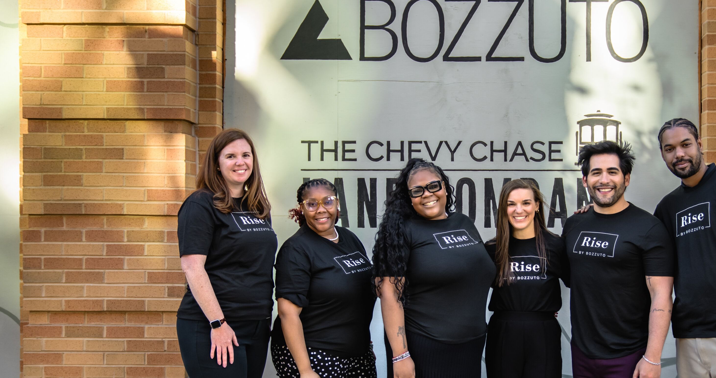 Group of six people wearing black shirts outside a Bozzuto office building.
