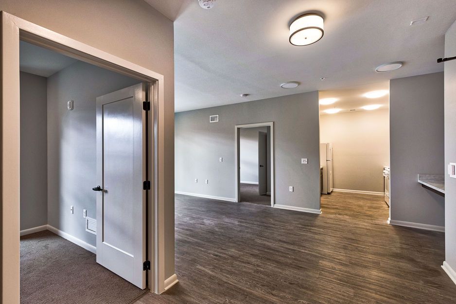 A spacious room with gray walls, hardwood flooring, and white doors leading to other areas.