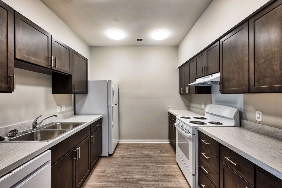 Modern kitchen with dark cabinets, white appliances, and a light-colored countertop.