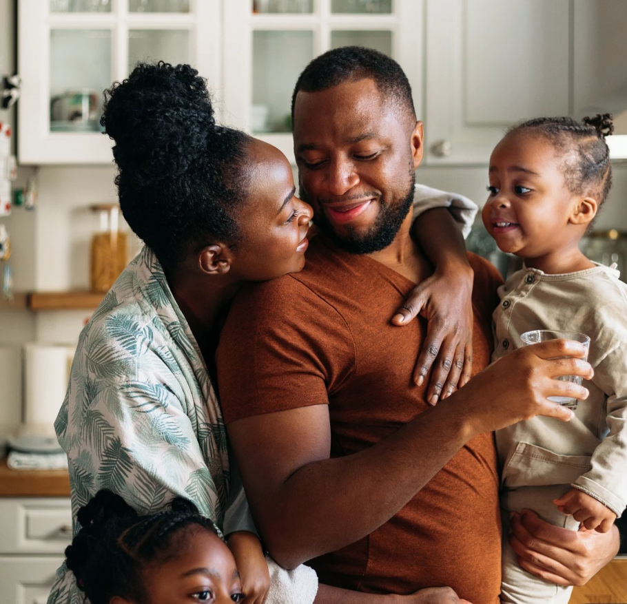 A family of four sharing a warm embrace in a cozy kitchen.