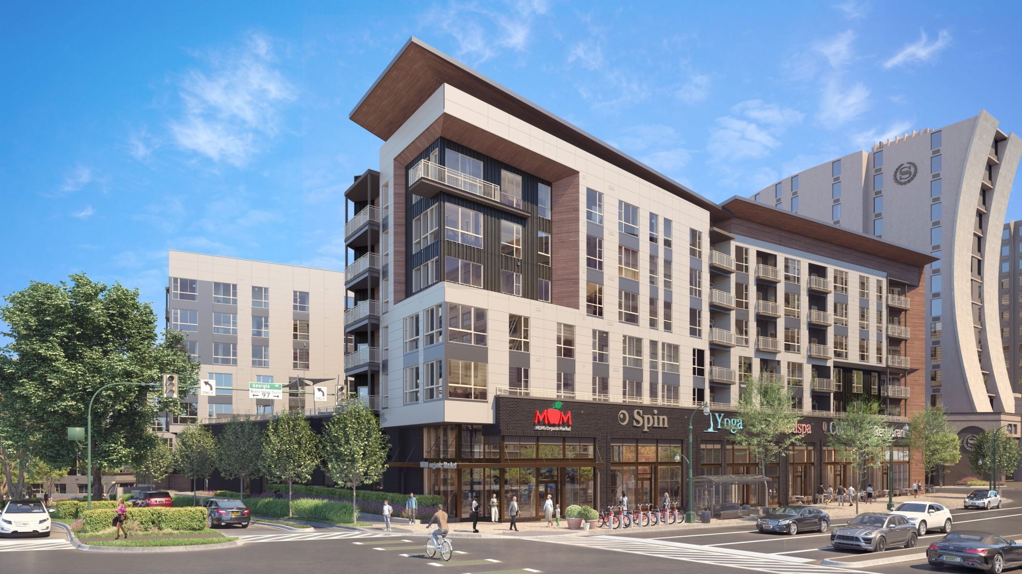 Modern multi-story apartment building with retail space and landscaped surroundings.