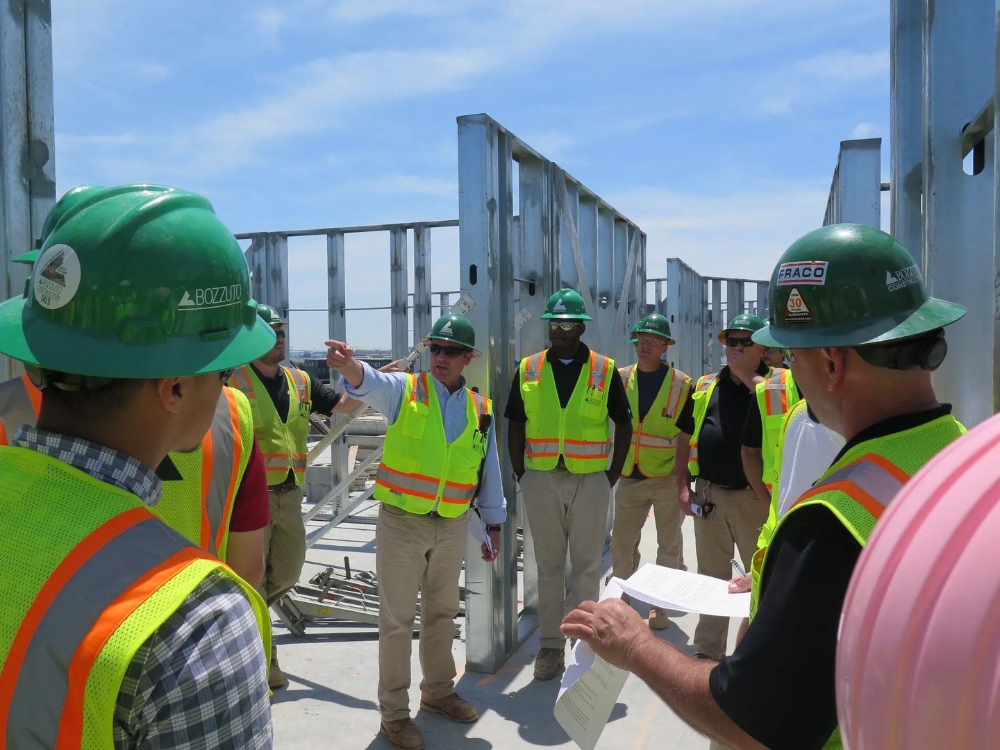 Group of construction workers in hard hats and vests discussing on a building site.