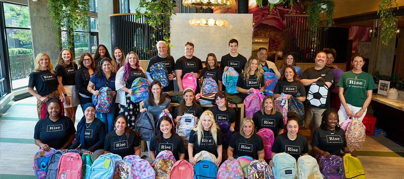 Group of people holding colorful backpacks in a community setting.