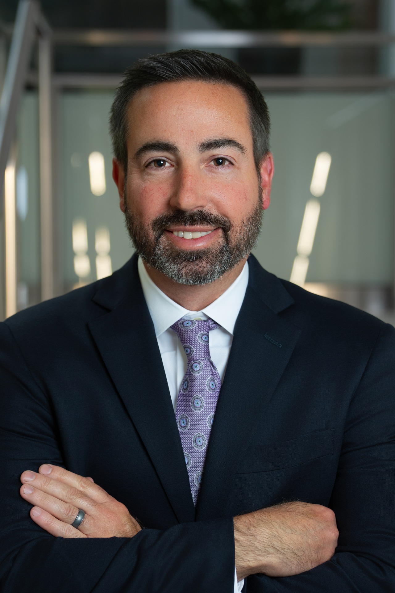 Mark Digby, a man with a beard, is wearing a suit and smiling in a modern office setting.