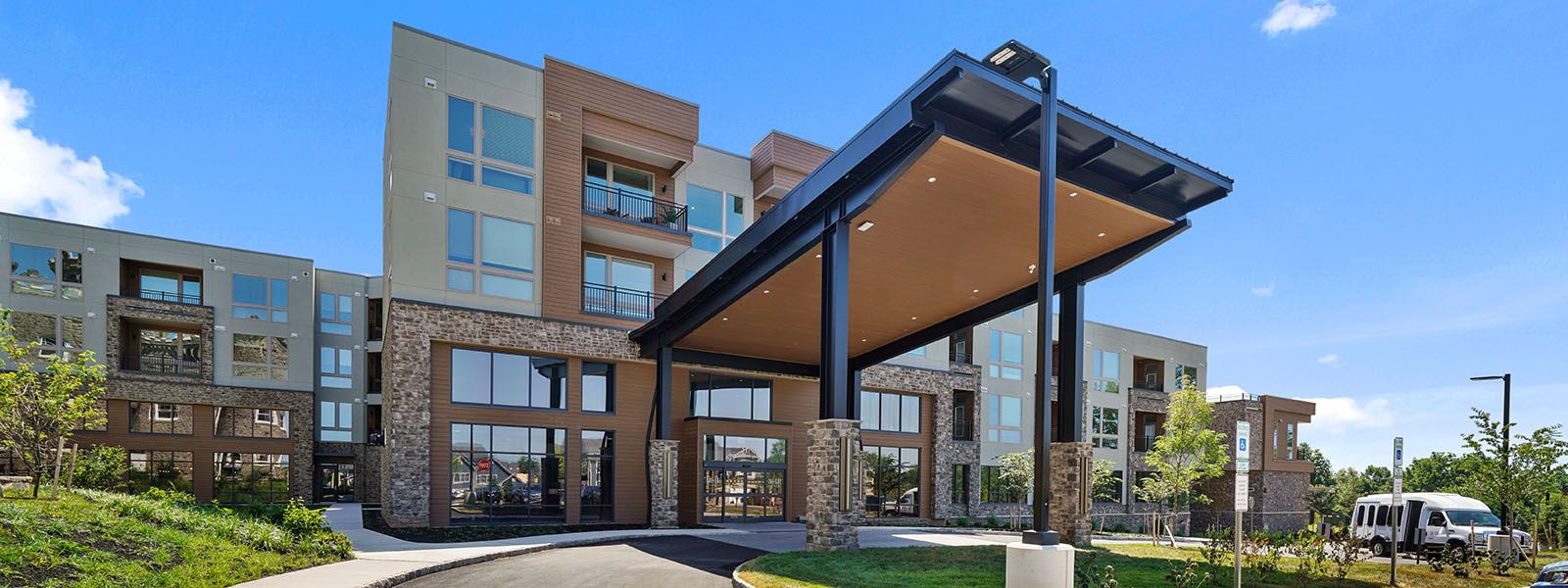 Modern multi-story building with a covered entrance and landscaped surroundings.