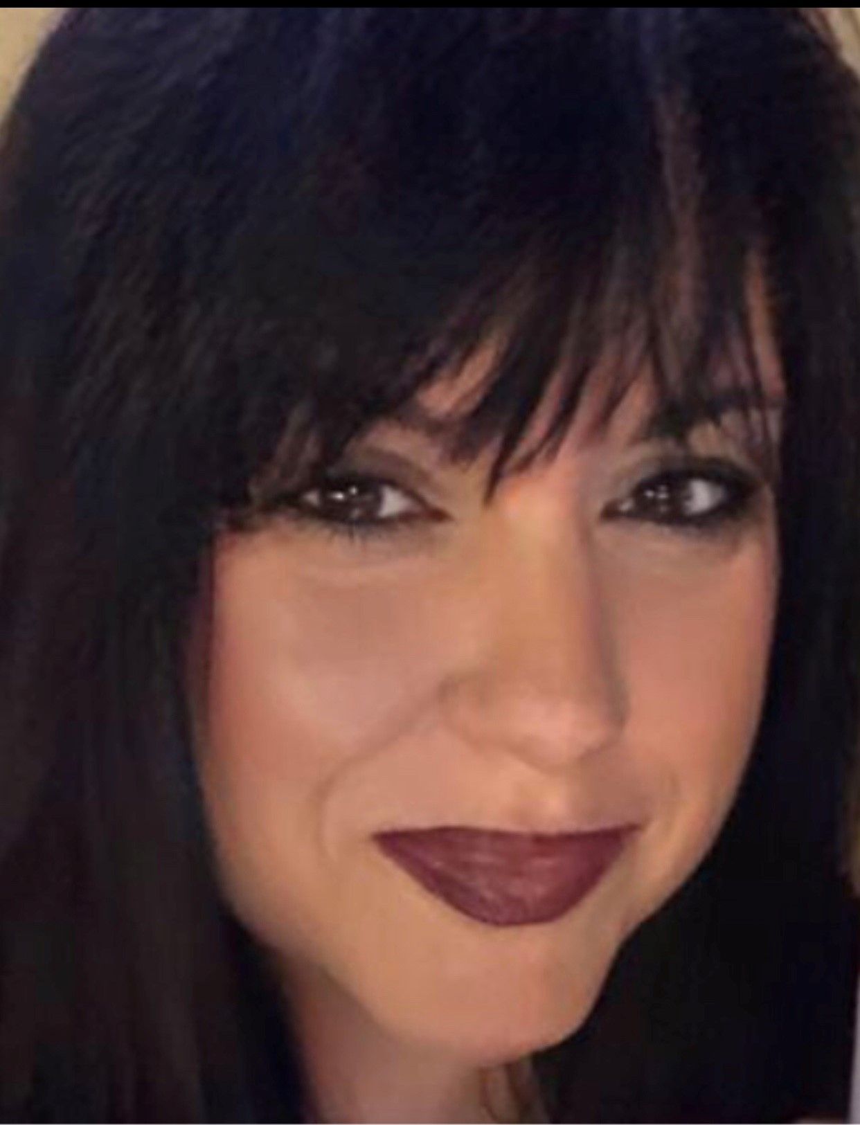 Close-up portrait of a woman with long dark hair and a subtle smile.