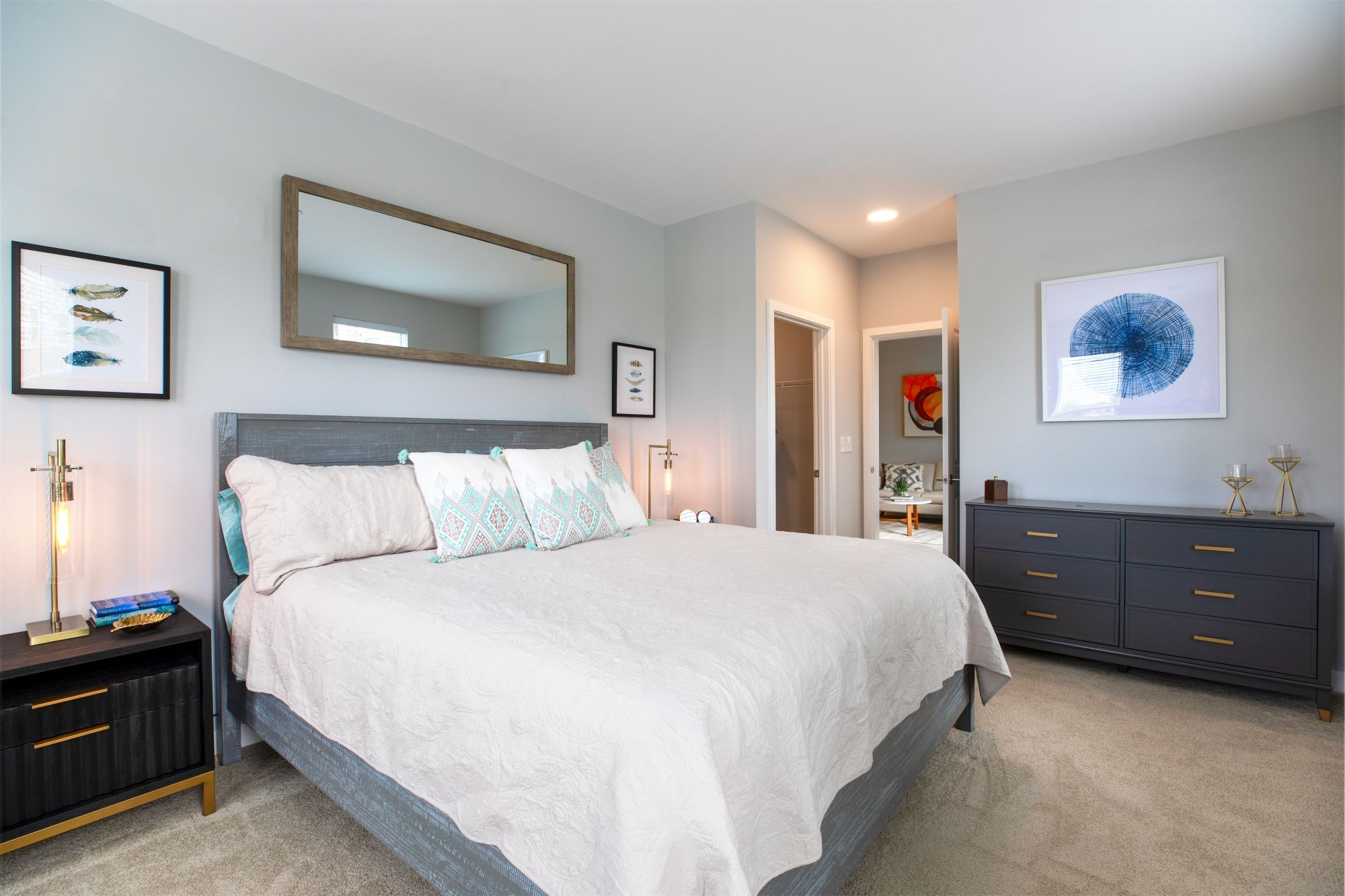 Modern bedroom with a bed, mirror, and dresser, featuring neutral colors and stylish decor.