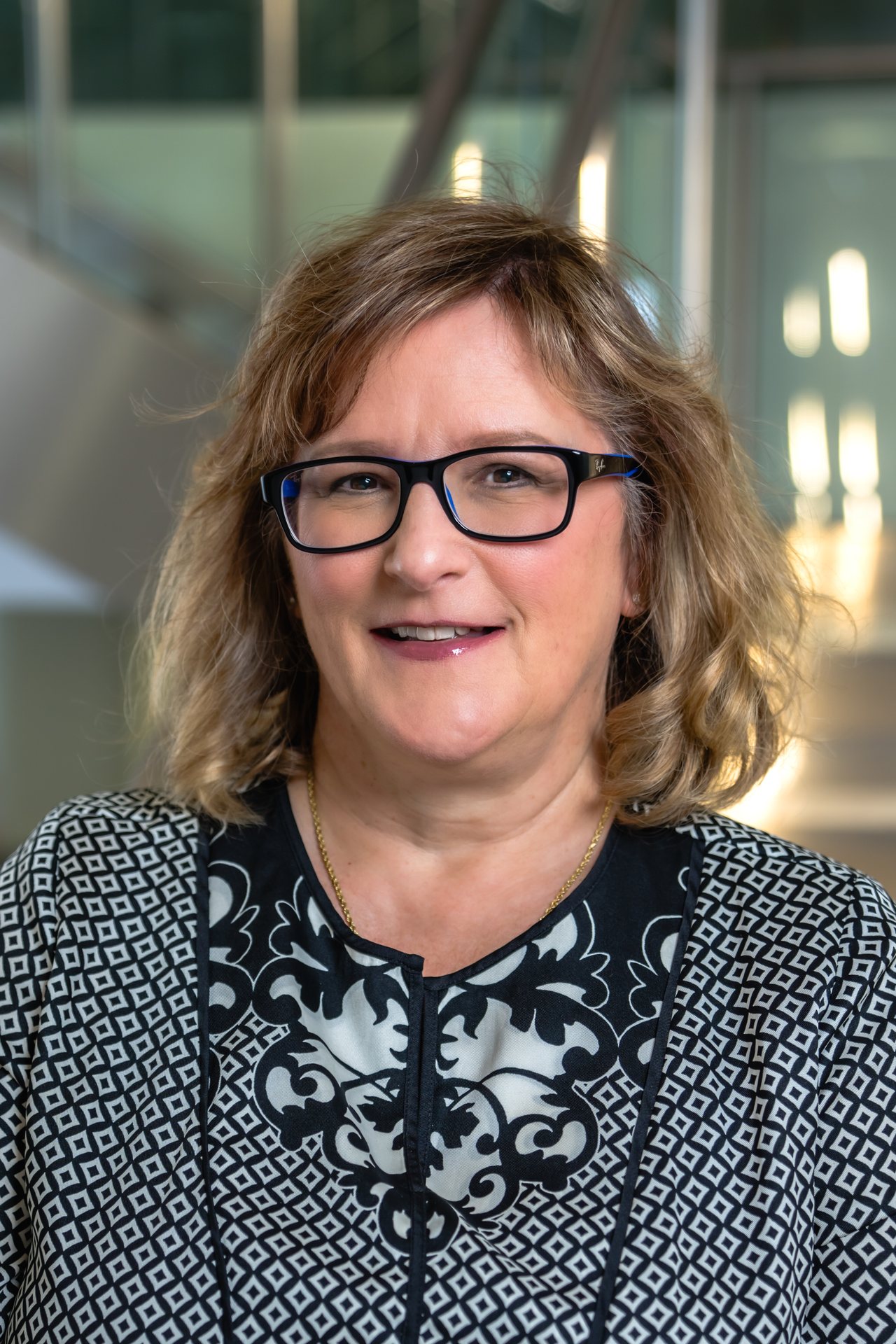 Portrait of Monica LaVorgna with glasses, smiling, against a blurred background.