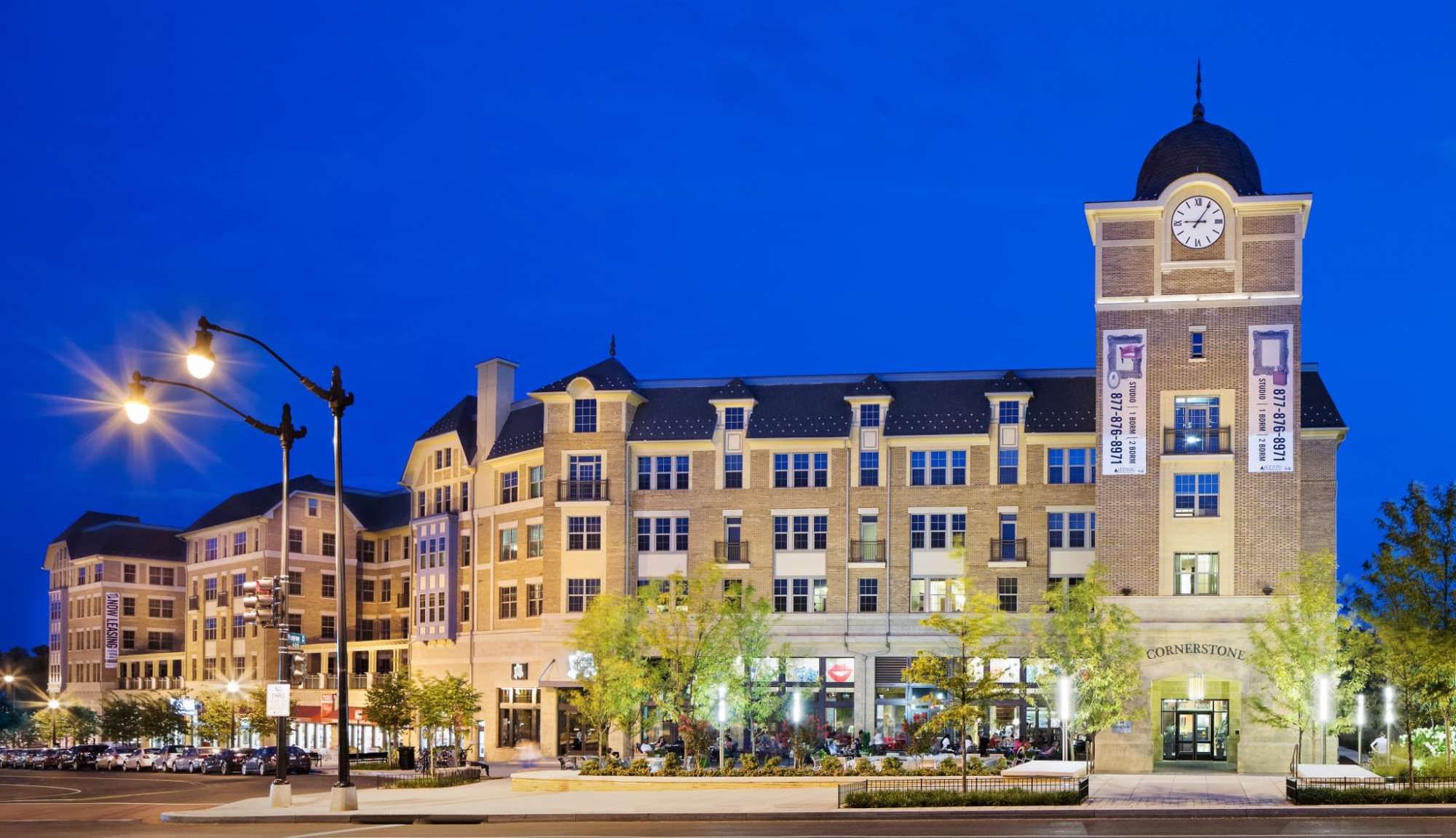 Modern building with a clock tower, illuminated at dusk.