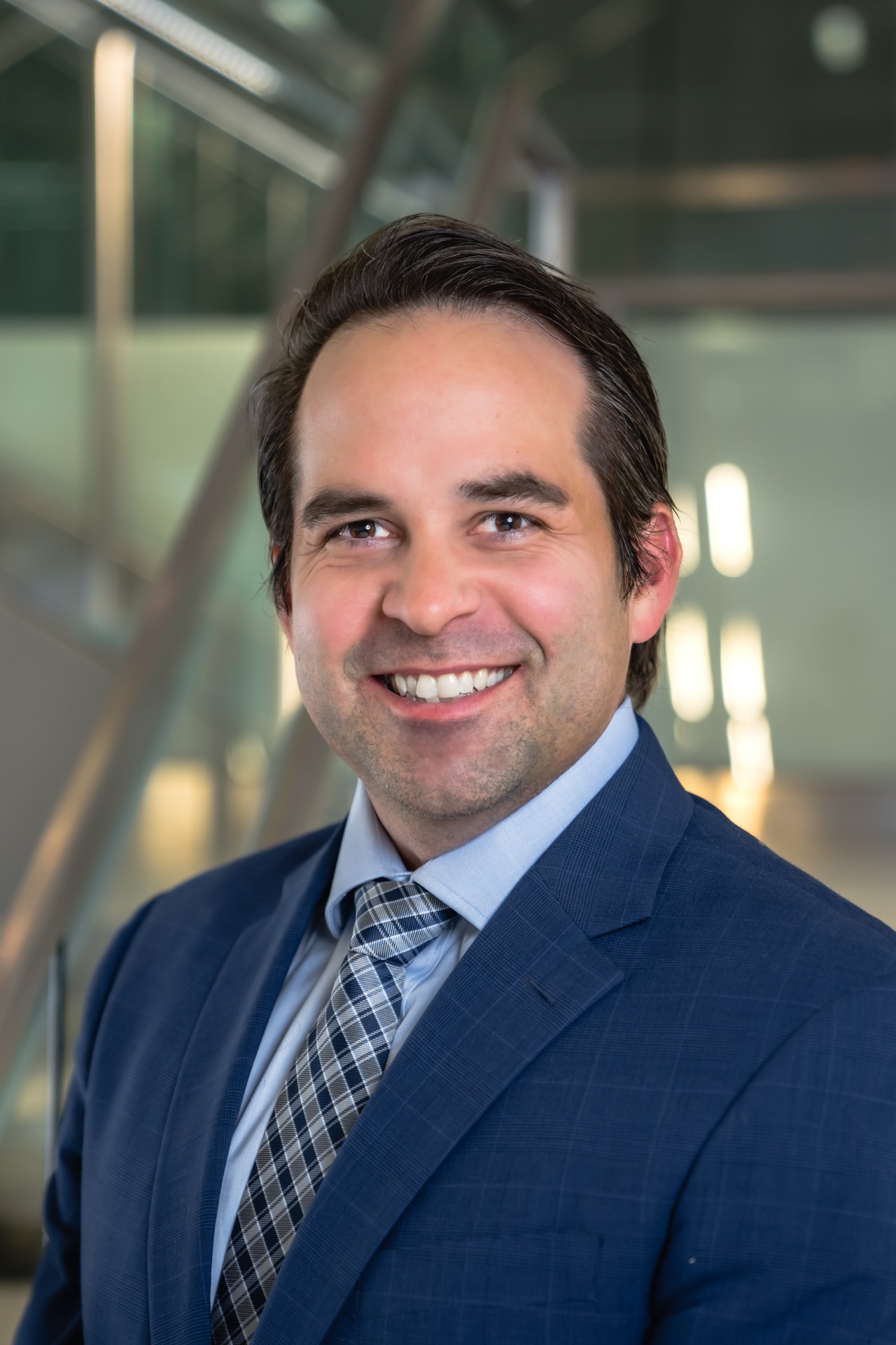 Professional portrait of Nicholas Umosella in a suit, smiling against a modern background.