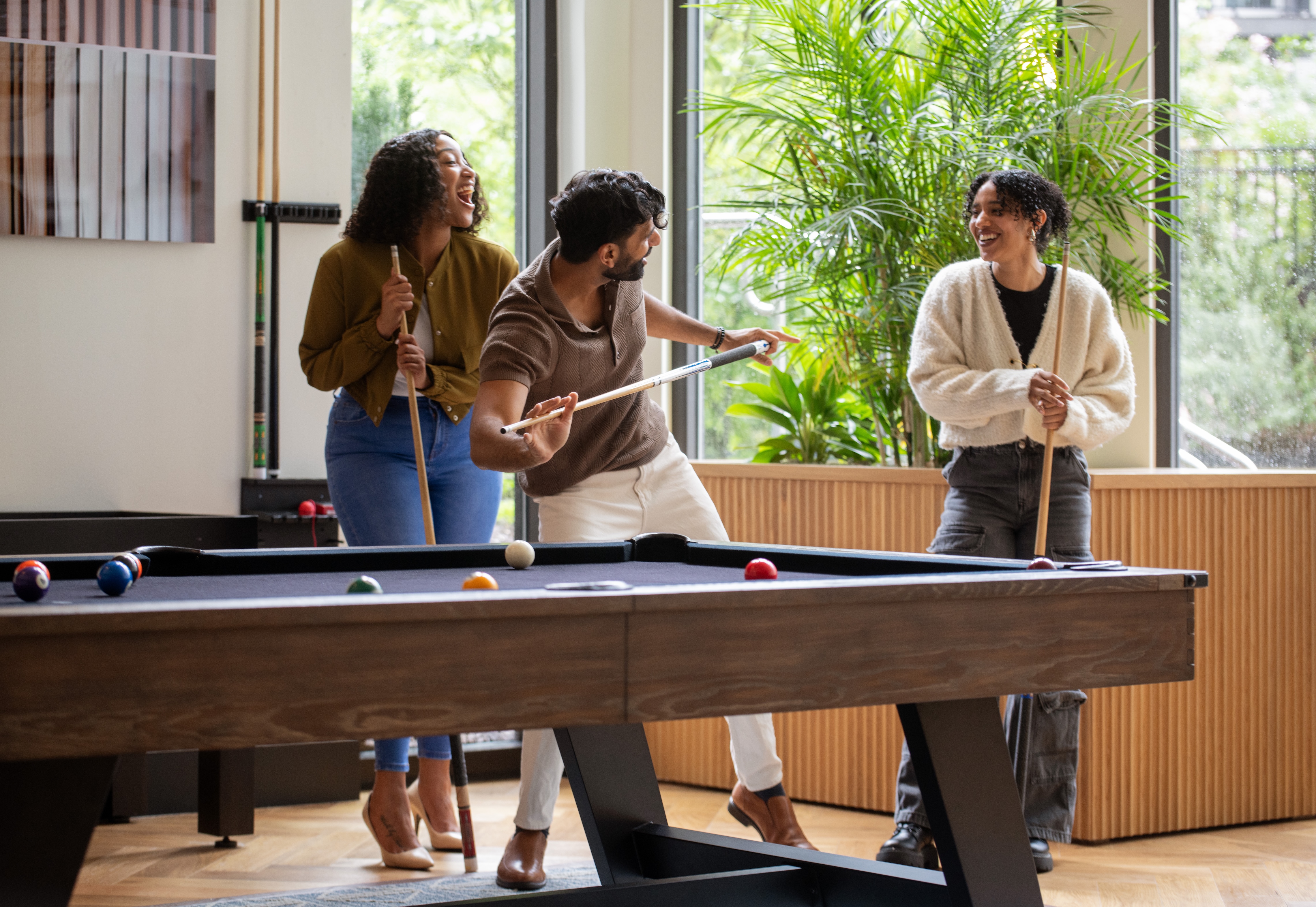 Three friends playing billiards in a cozy game room.