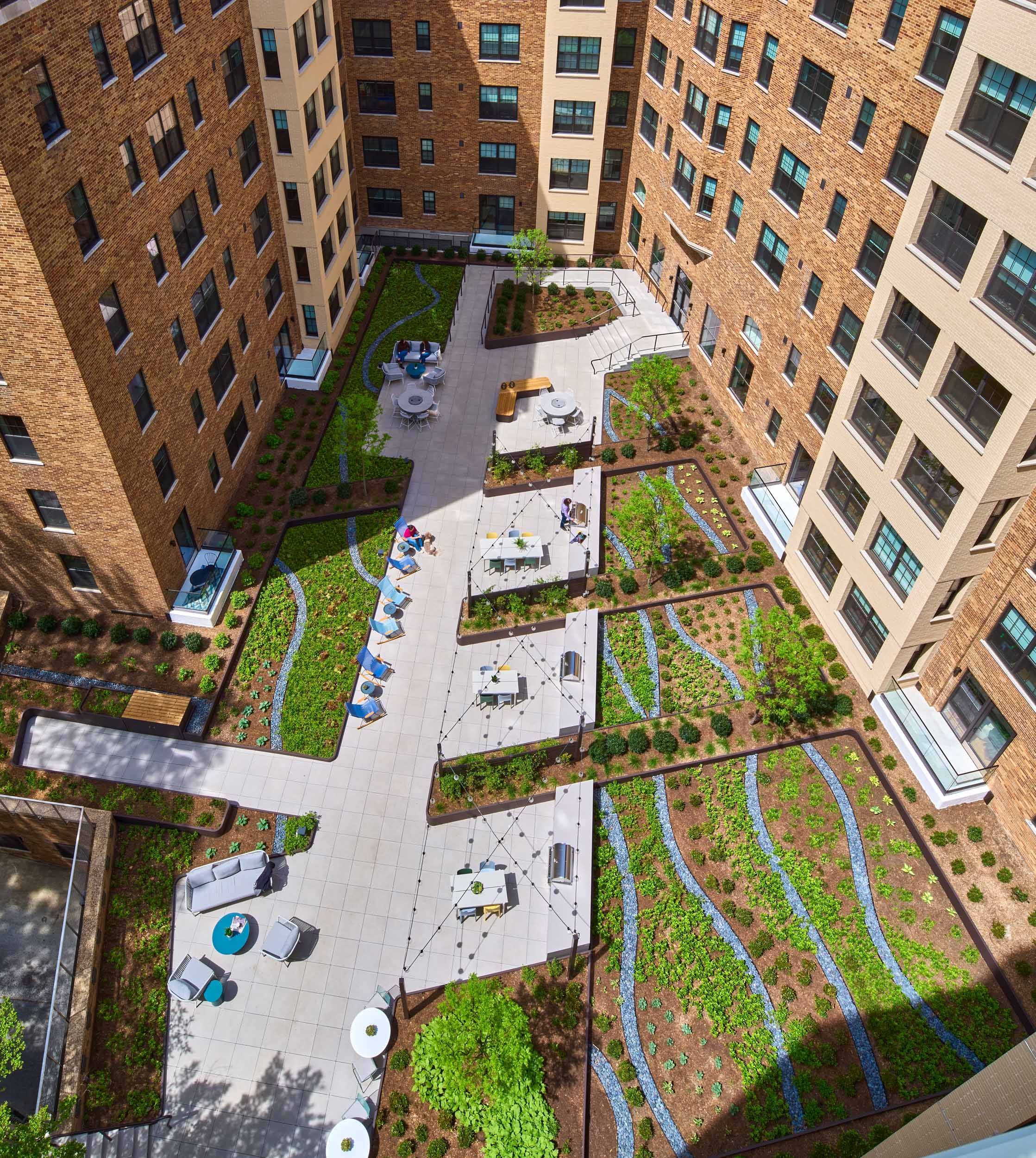 Aerial view of a courtyard with paths, grass, and seating amidst modern brick buildings.