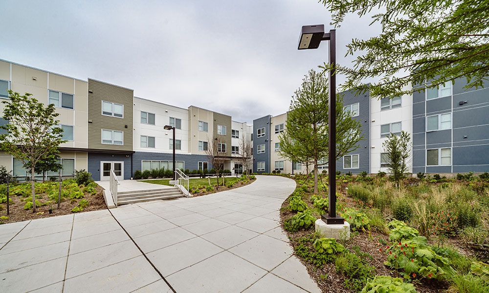 Modern apartment building with a landscaped pathway and greenery.