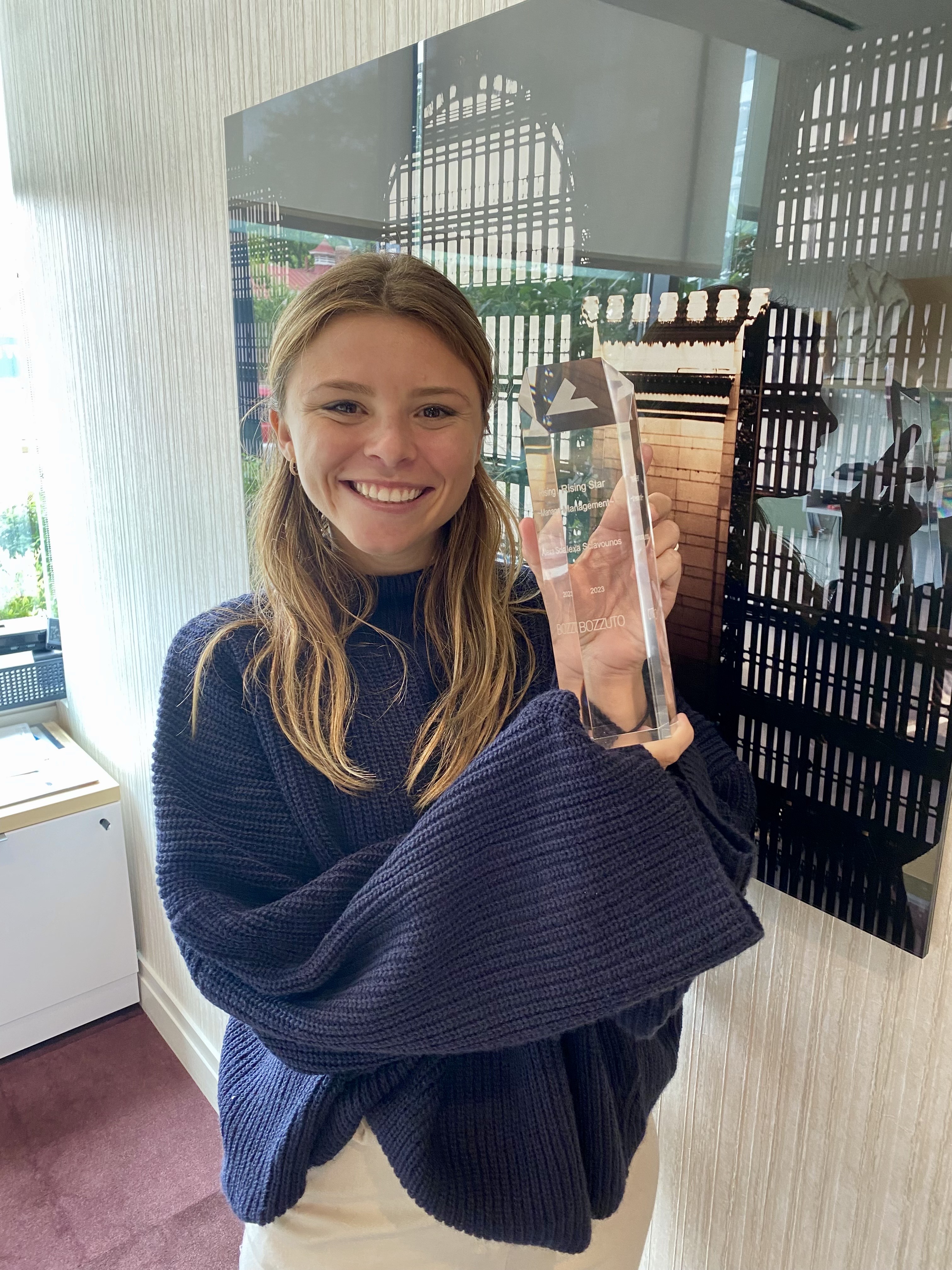 A smiling young woman wearing a dark shawl holds a clear tube.