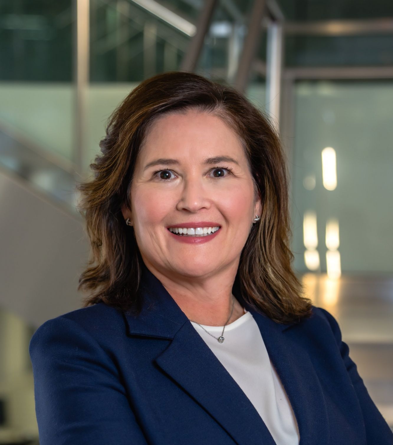 Smiling woman in professional attire, standing in an office environment.