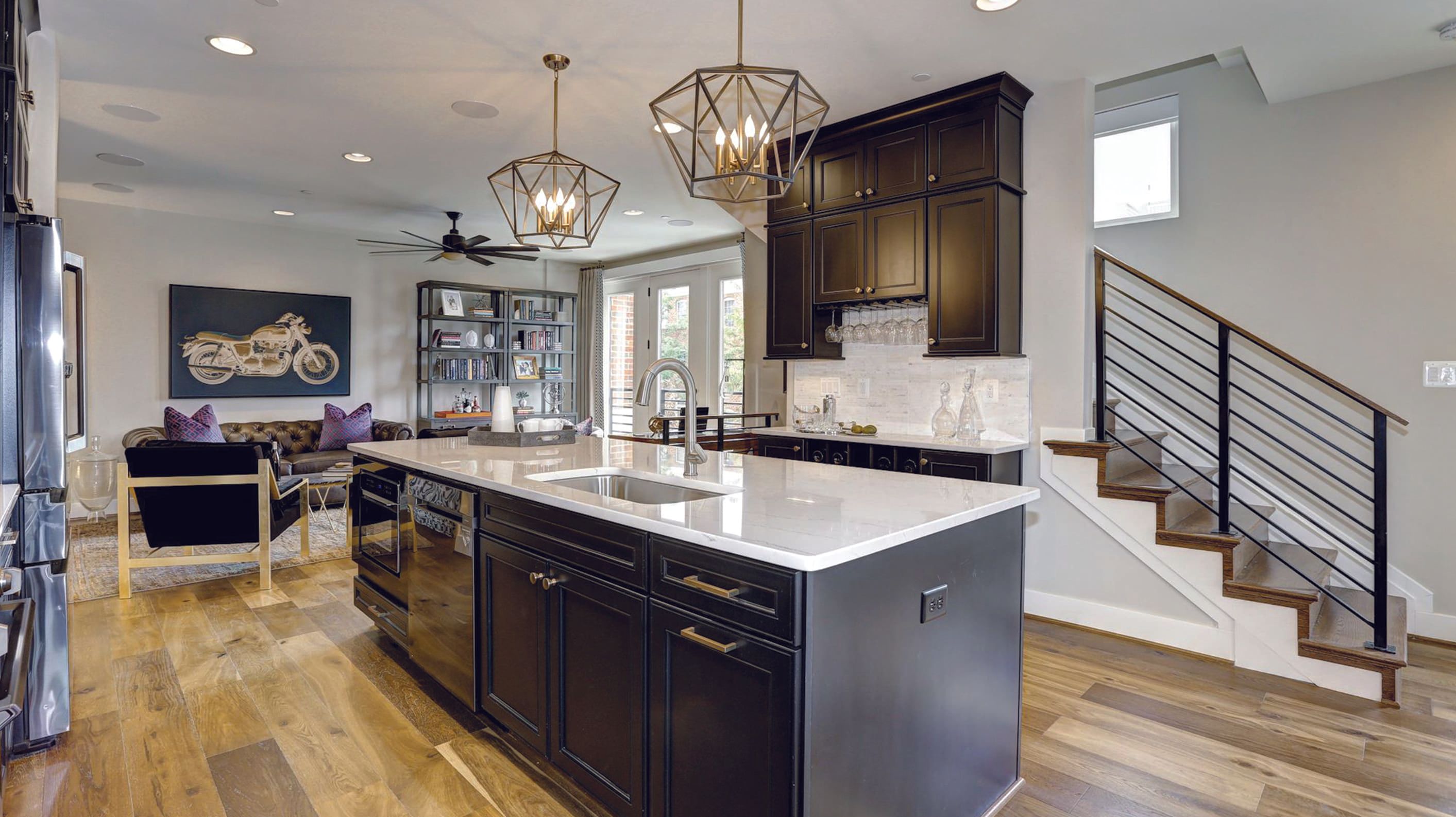 Modern kitchen with dark cabinets, an island, and elegant lighting.