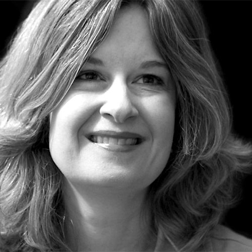 Black and white portrait of a woman with wavy hair smiling gently.