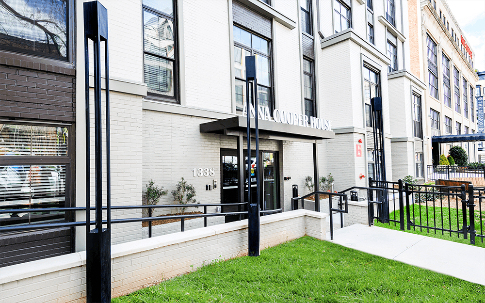 Modern building entrance with green grass and decorative posts.