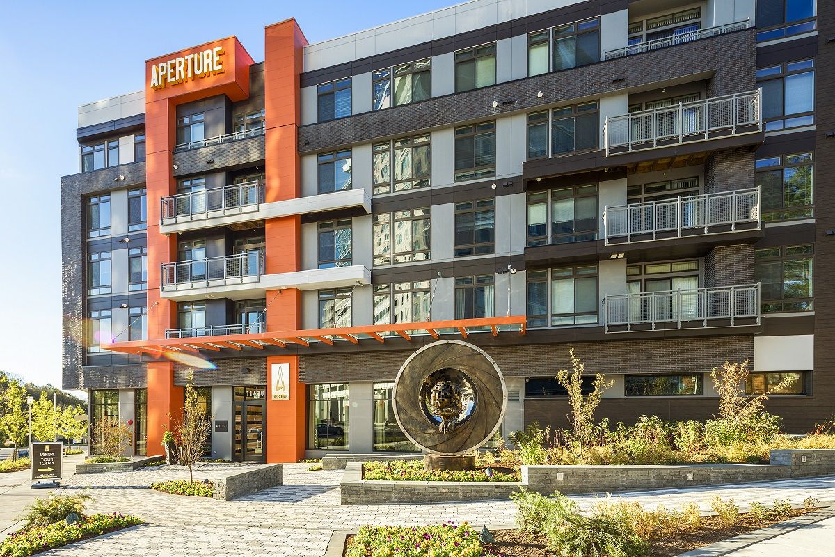 Modern apartment building with a feature sculpture and landscaped entrance.