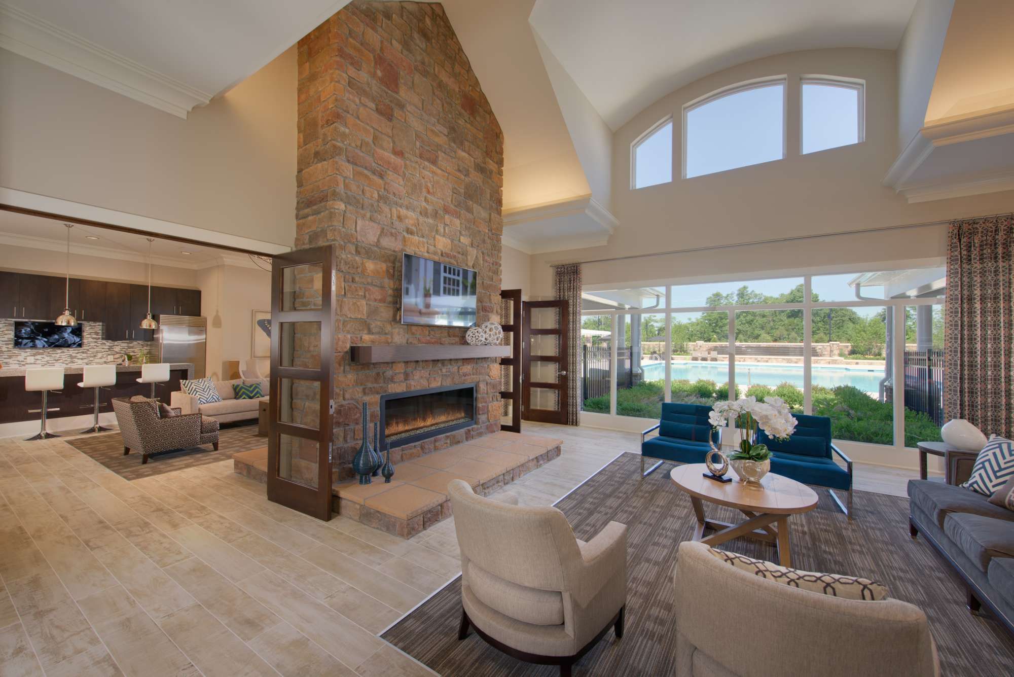 Bright, modern living room with a stone fireplace and large windows, overlooking an outdoor area.