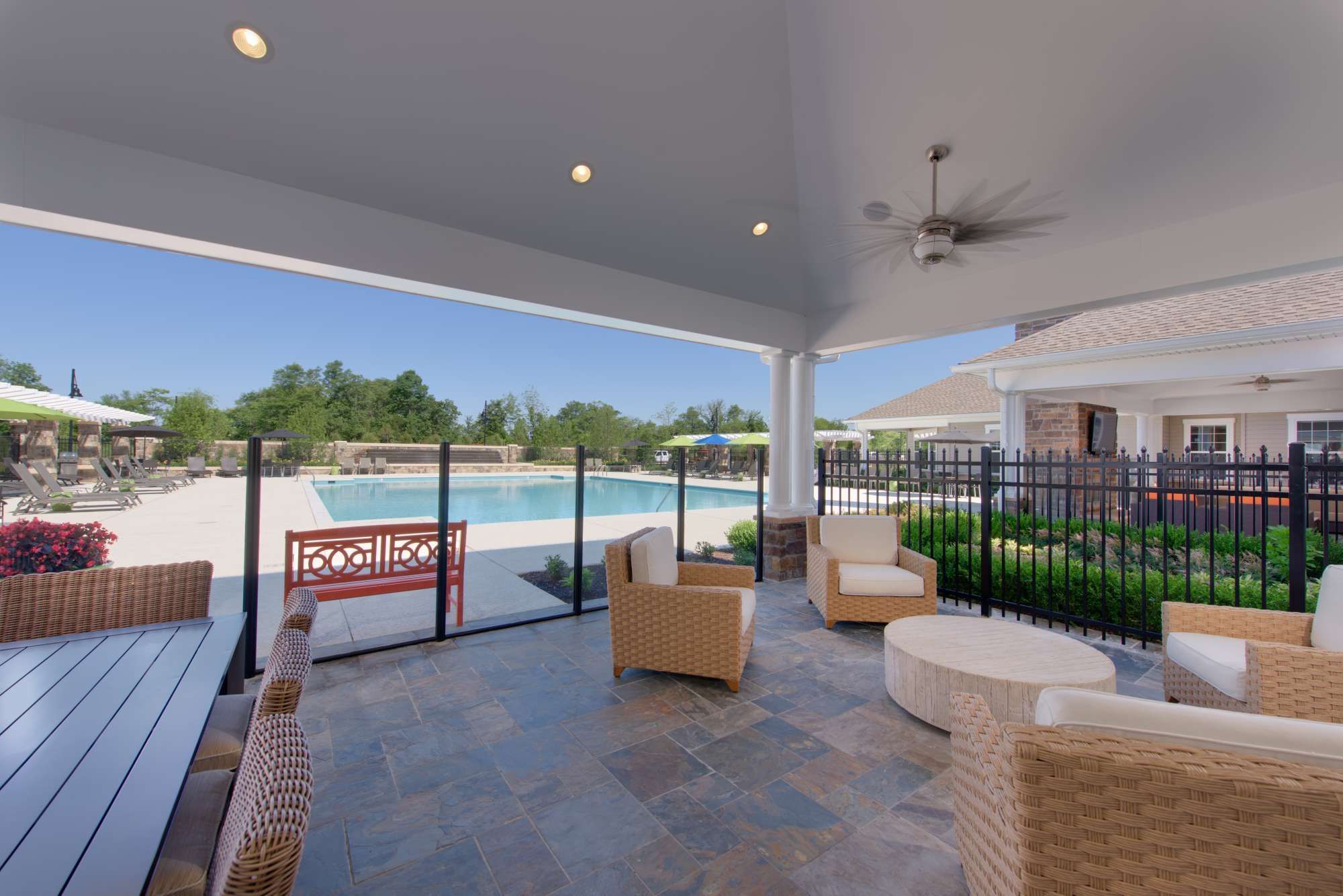 A patio with lounge chairs overlooking a pool surrounded by greenery.
