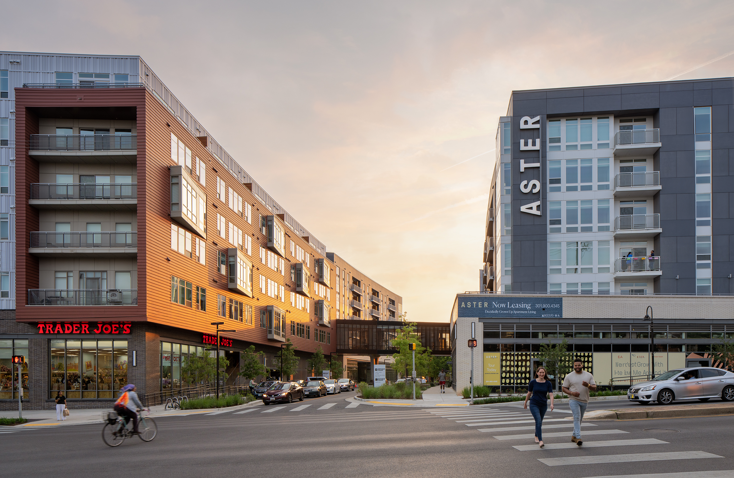 Modern buildings at sunset with pedestrians crossing the street.