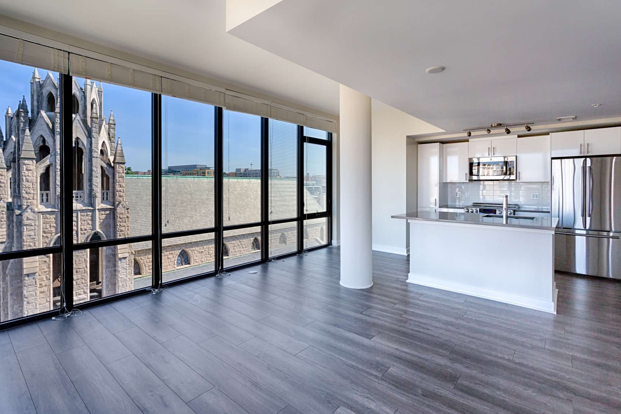 Modern apartment interior with large windows showcasing a view of a church tower outside.