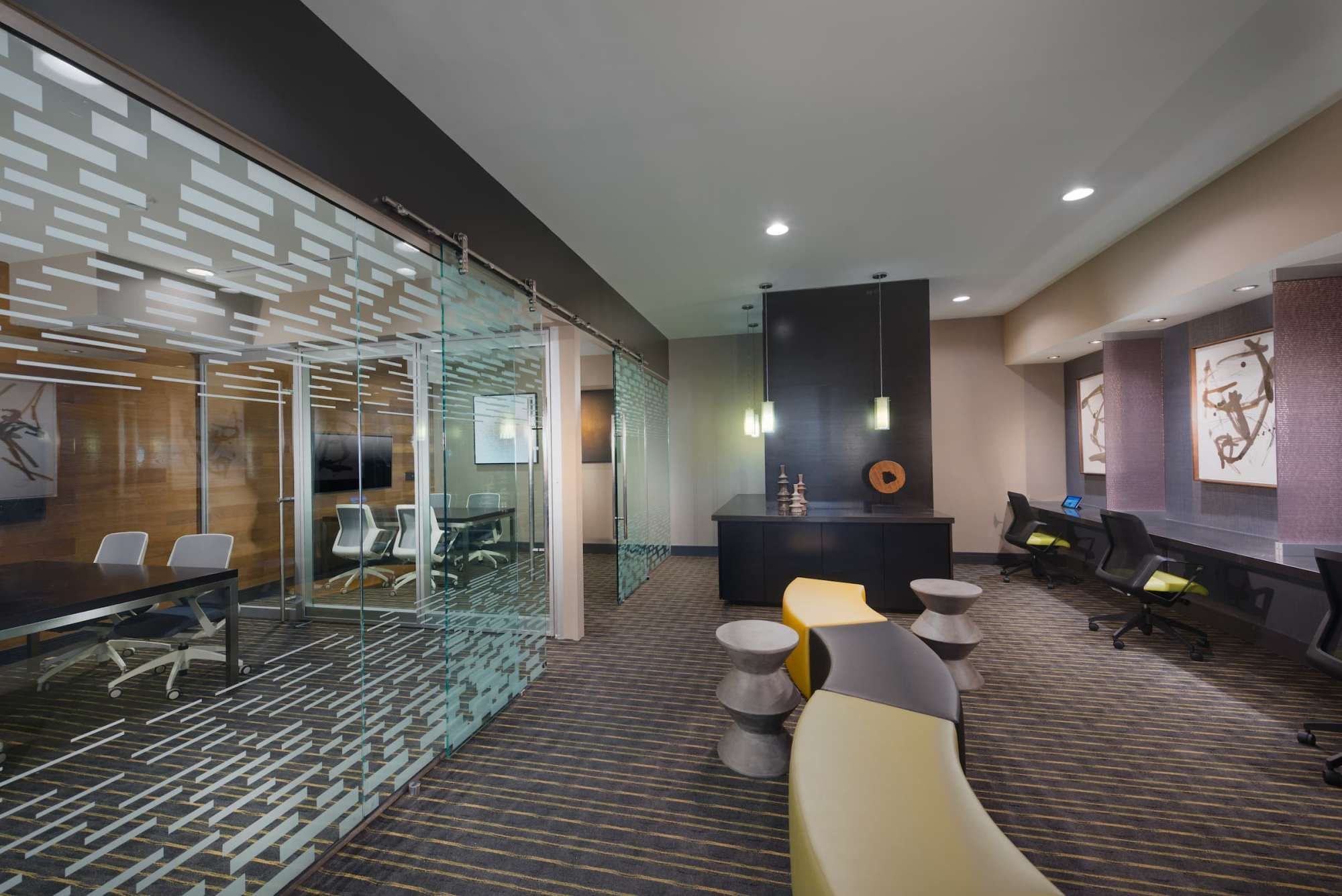 Modern office lobby with glass meeting room and sleek furniture.
