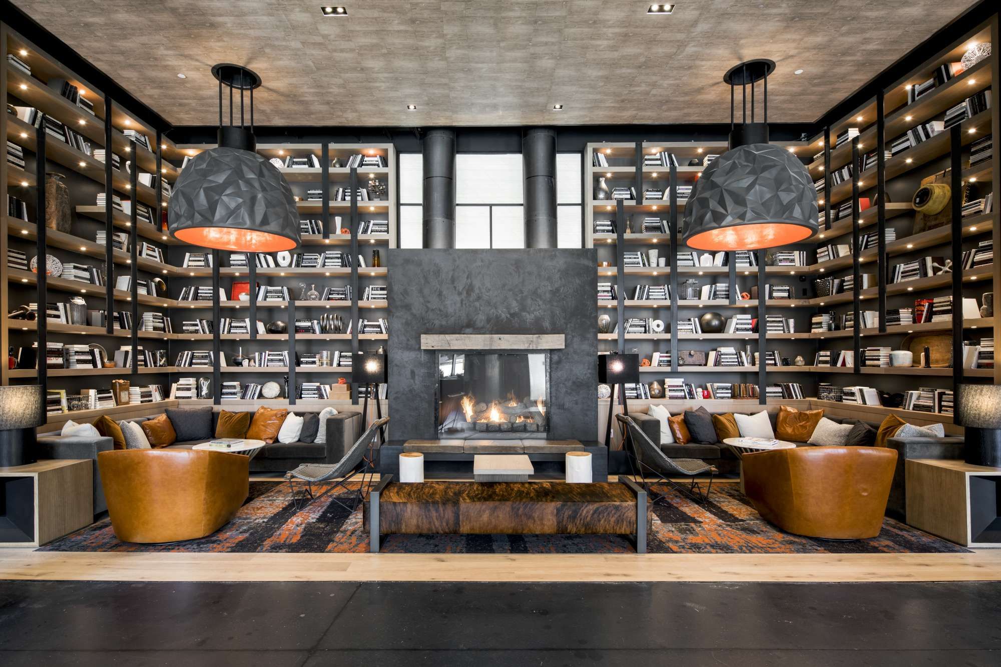 Cozy library with a fireplace, leather chairs, and large bookshelves.