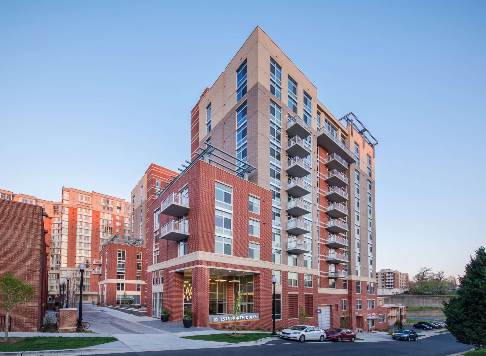 Modern multi-story apartment building with red brick and glass exteriors.