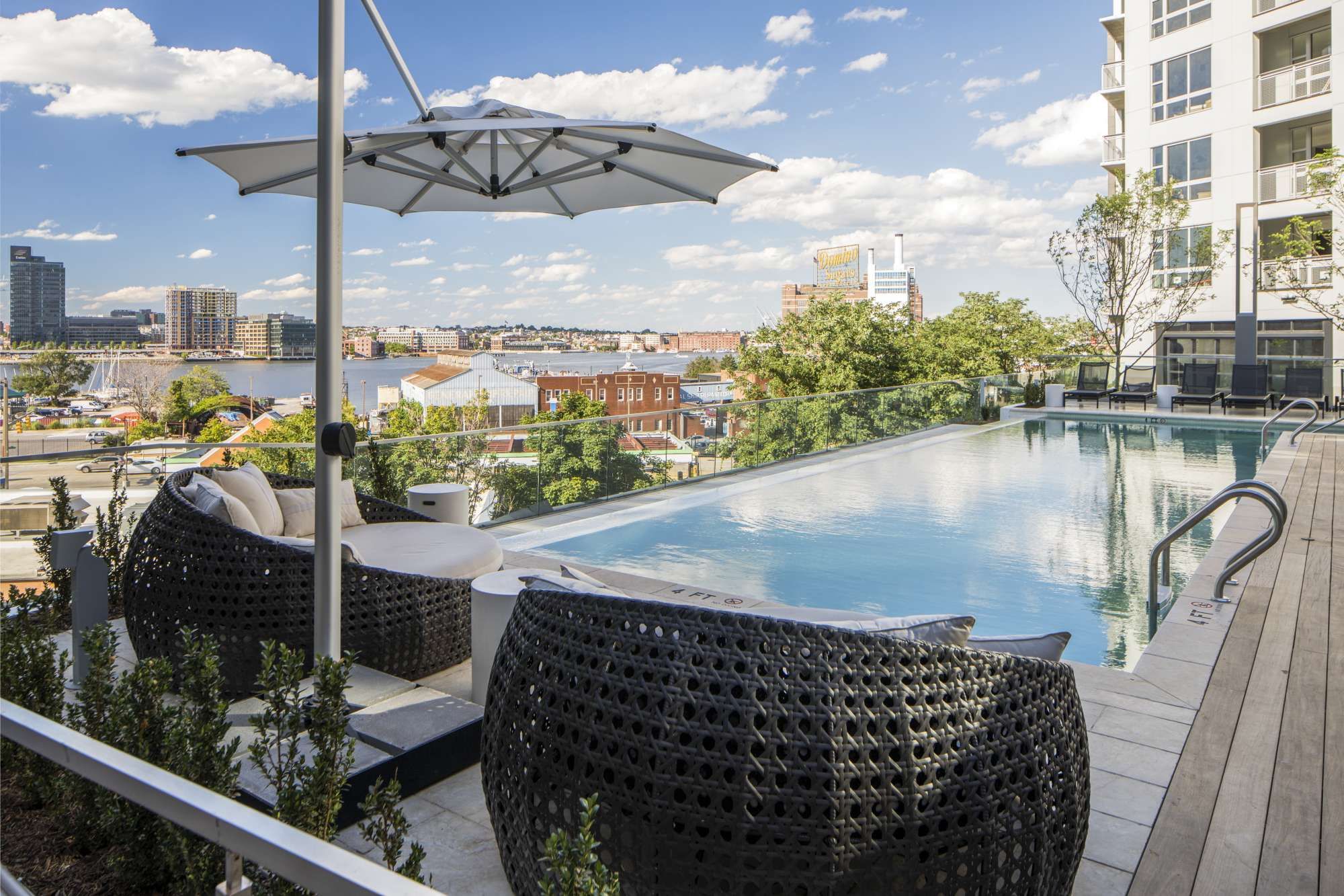 Rooftop pool area with lounge chairs and an umbrella overlooking a scenic city view.