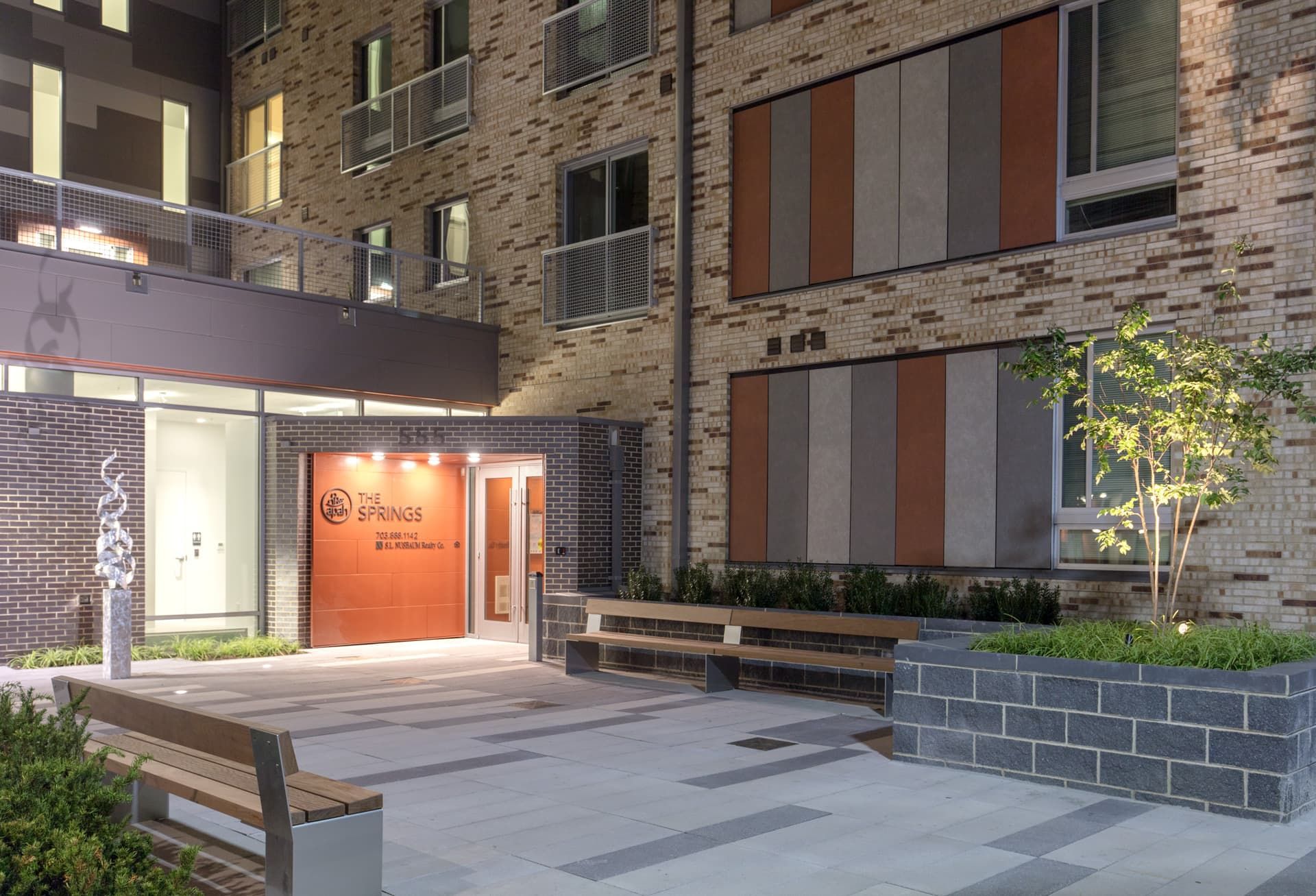 Modern apartment building entrance with decorative facades and greenery.
