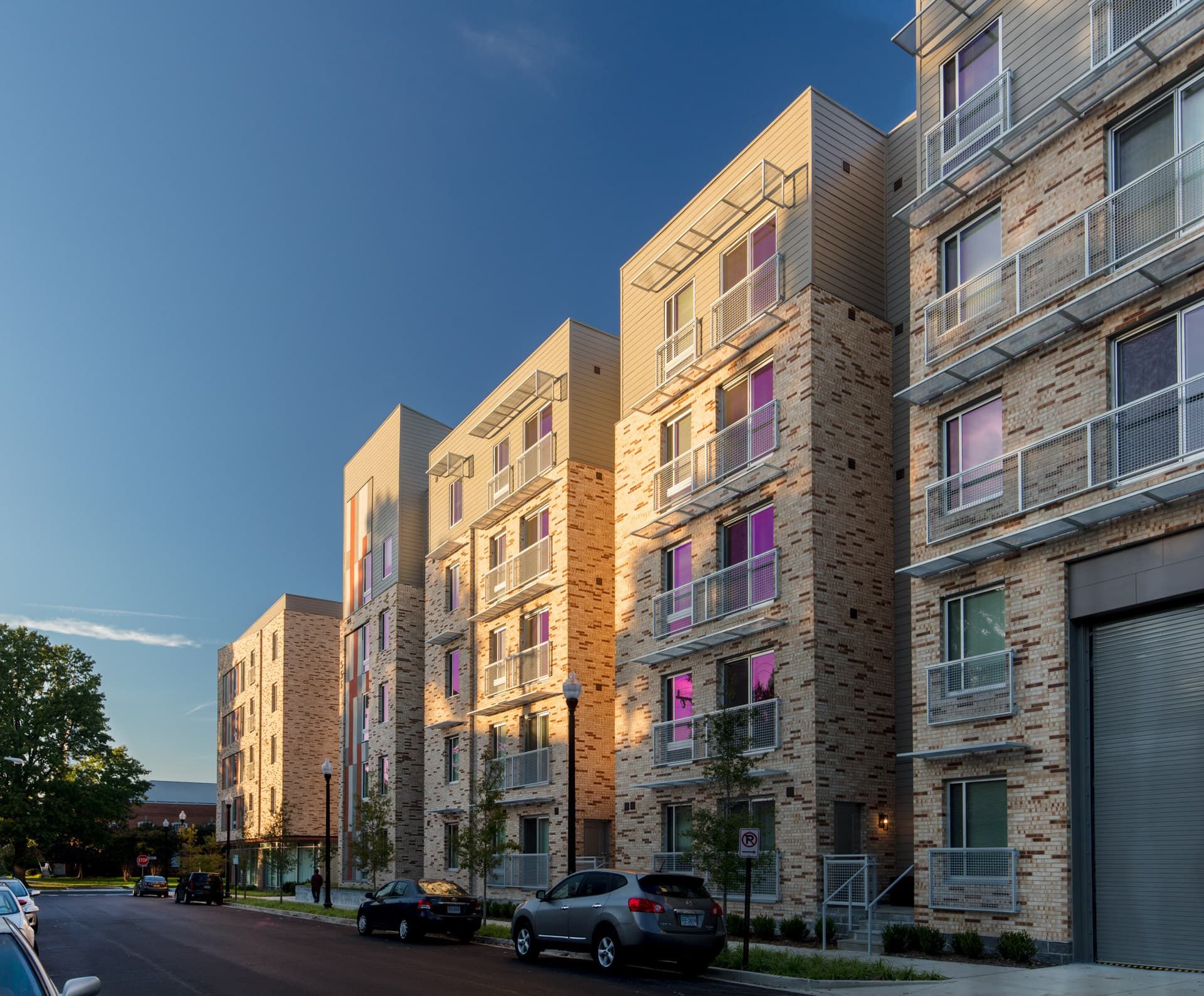 Modern brick apartments with large windows under a clear blue sky.