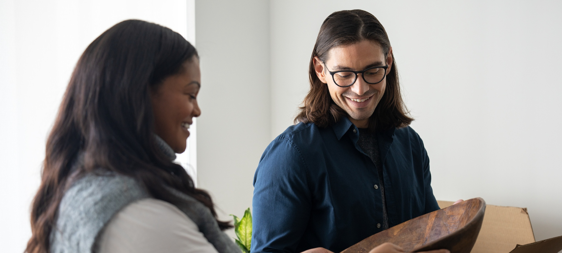 Two people examining a wooden object indoors.