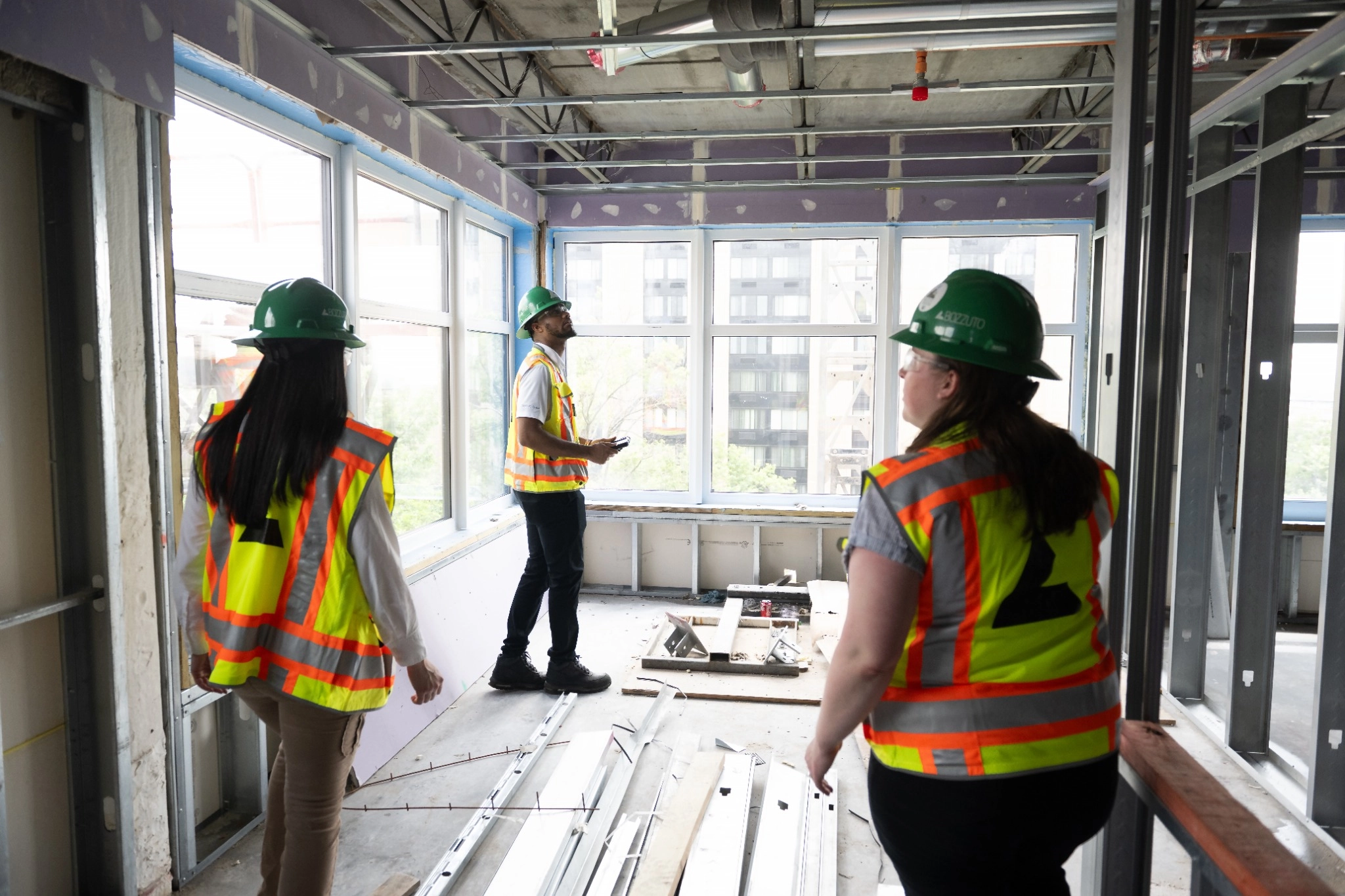 Three construction workers in hard hats in a partially finished room.