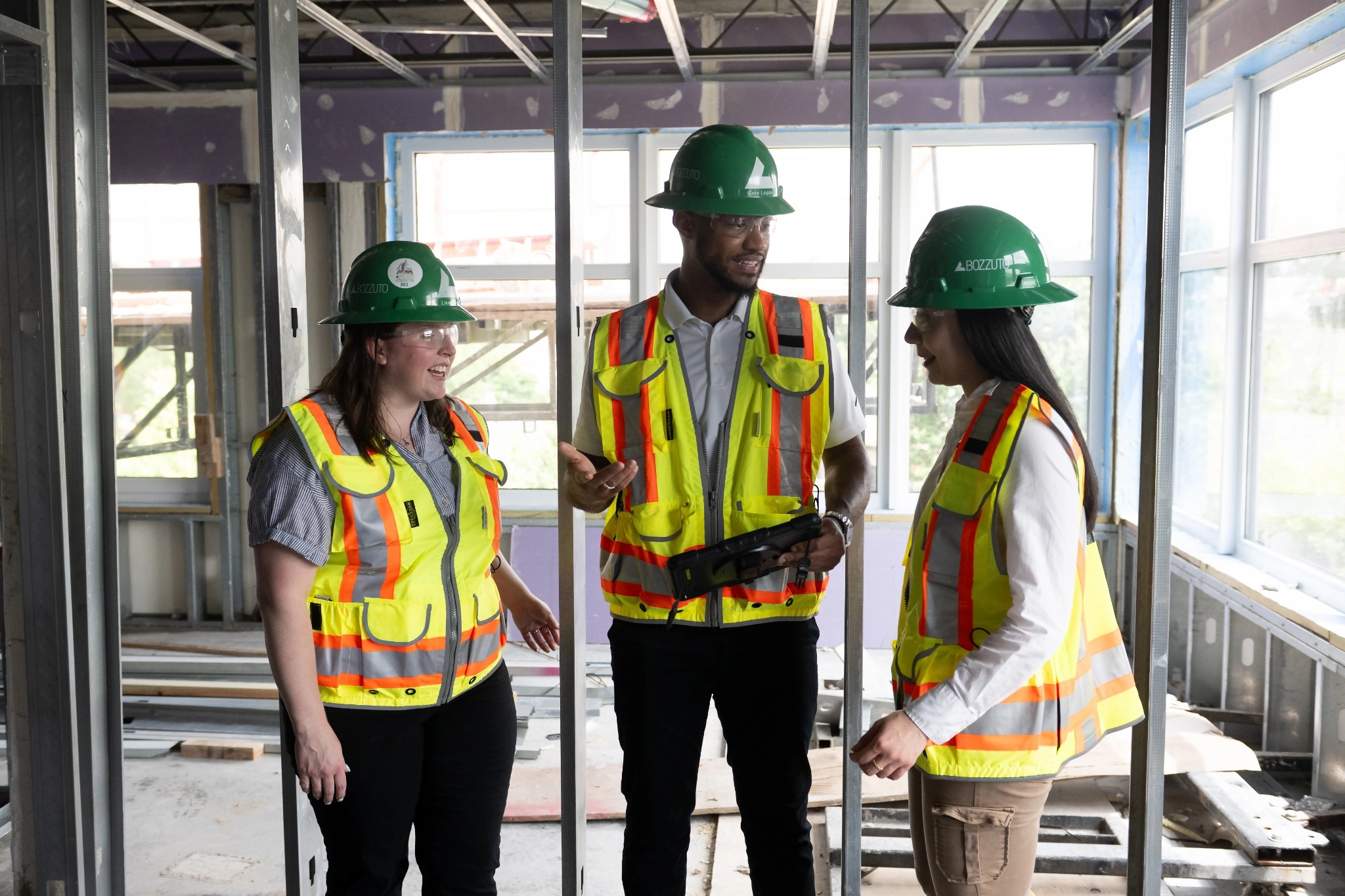 Three construction workers in hard hats discussing in a building under renovation.